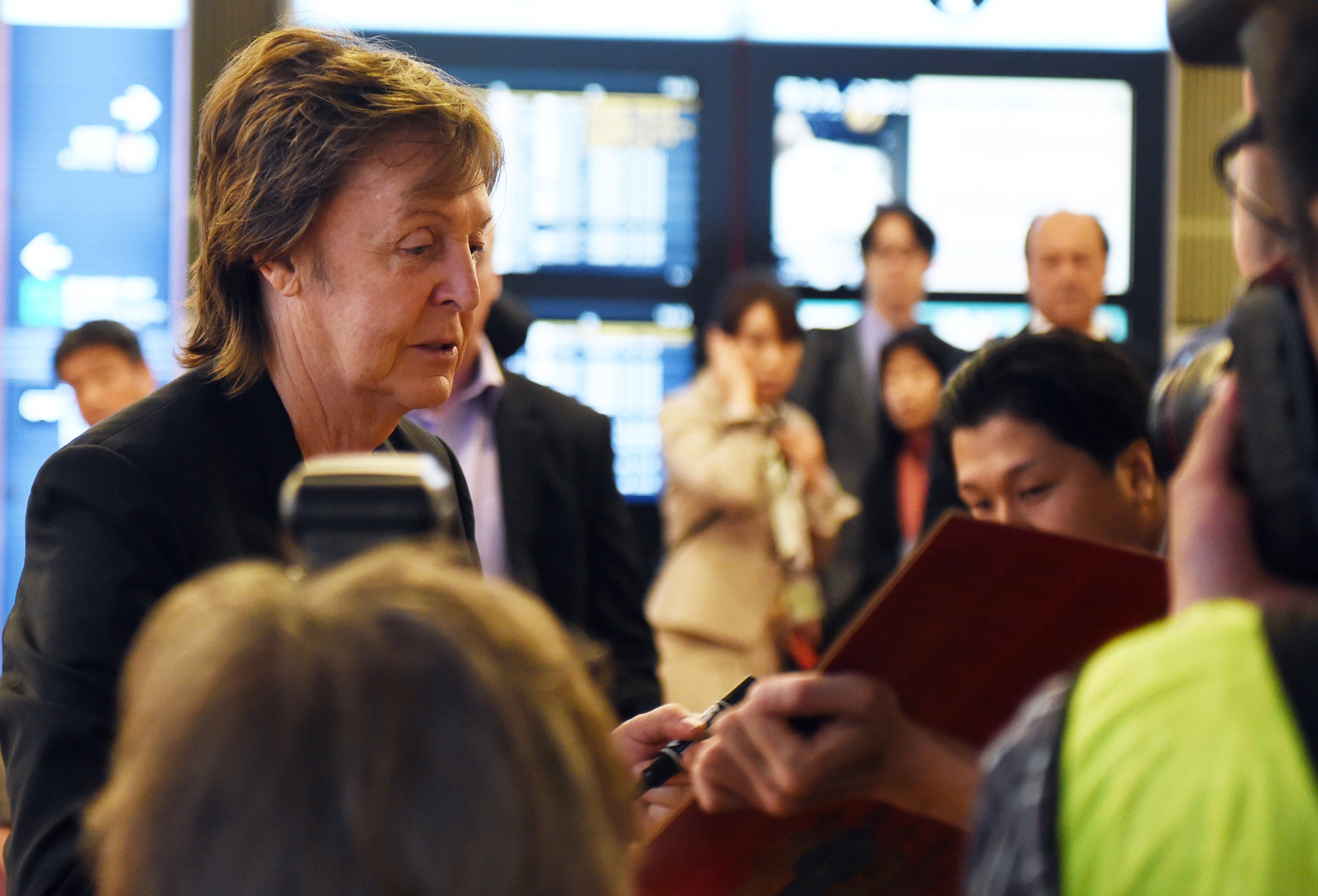 Paul McCartney firma su autógrafo a los fans a su llegada al aeropuerto de Haneda en Tokio el 15 de mayo de 2014. | Fuente: Getty Images