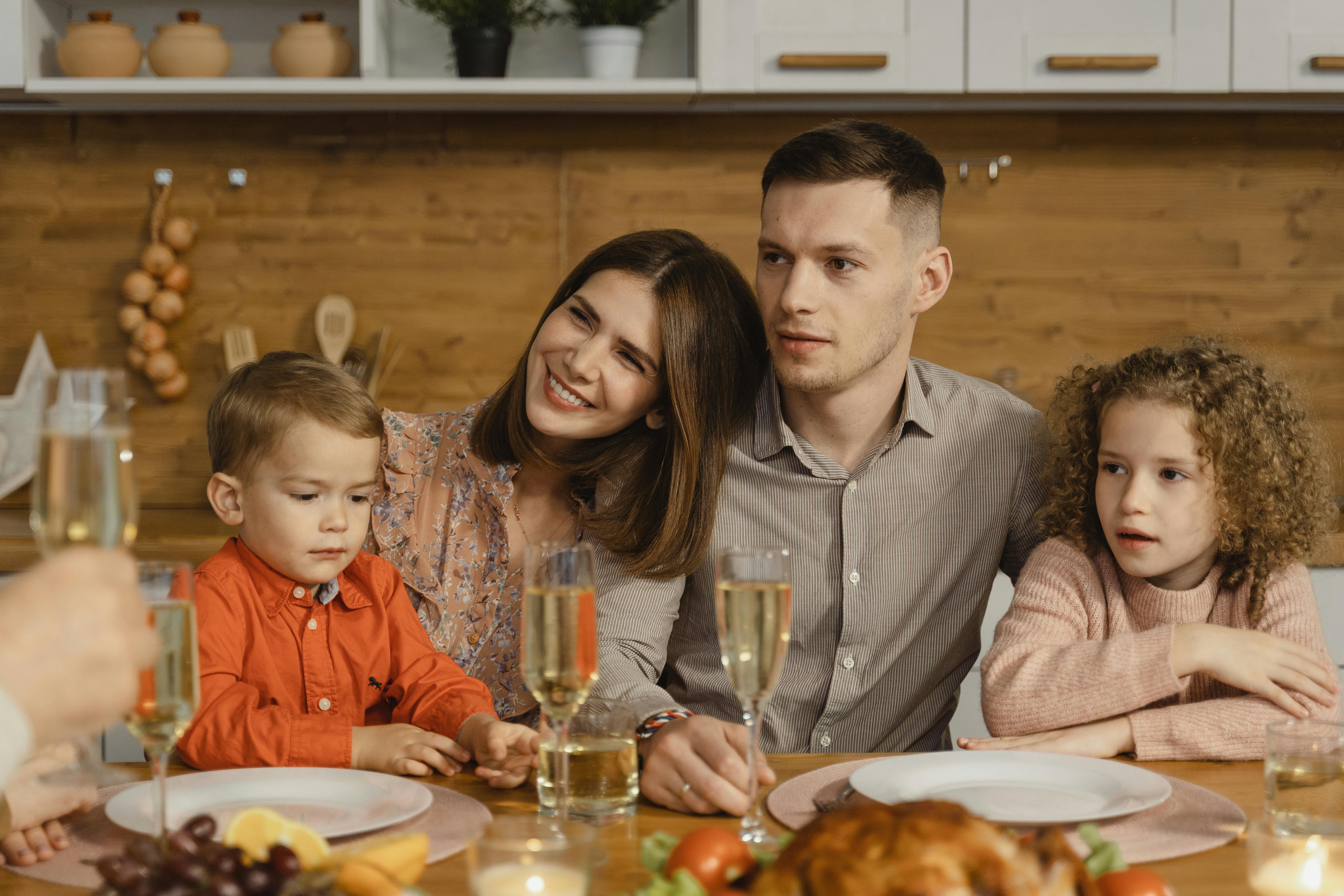 Una familia de cuatro miembros sentados juntos para comer | Fuente: Pexels
