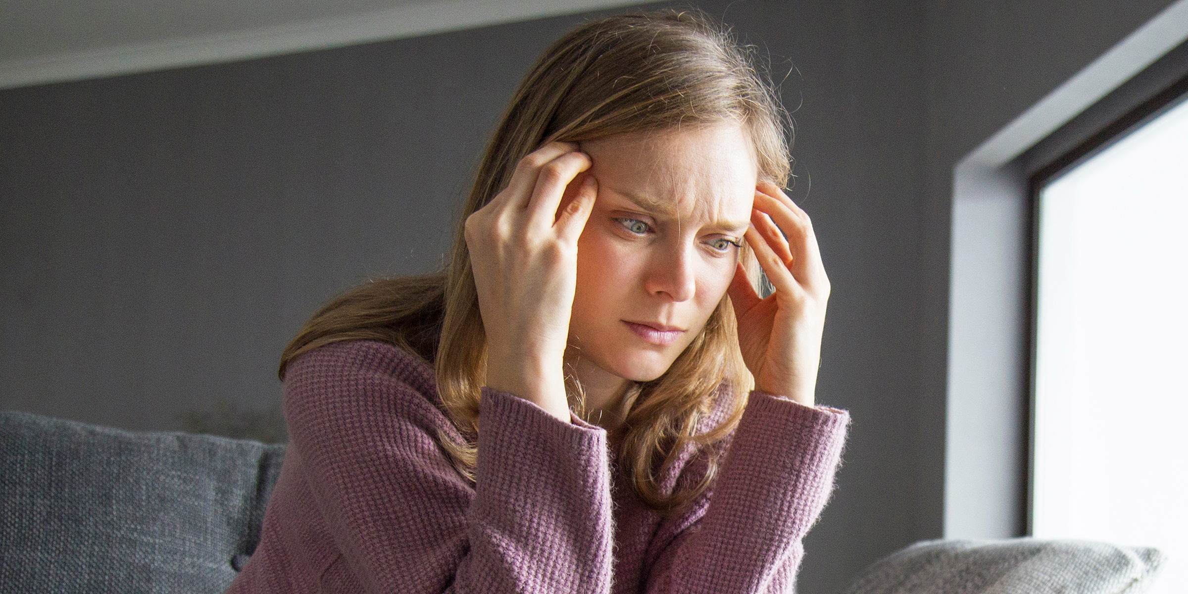 Una mujer preocupada presionándose las sienes con los dedos | Fuente: Shutterstock