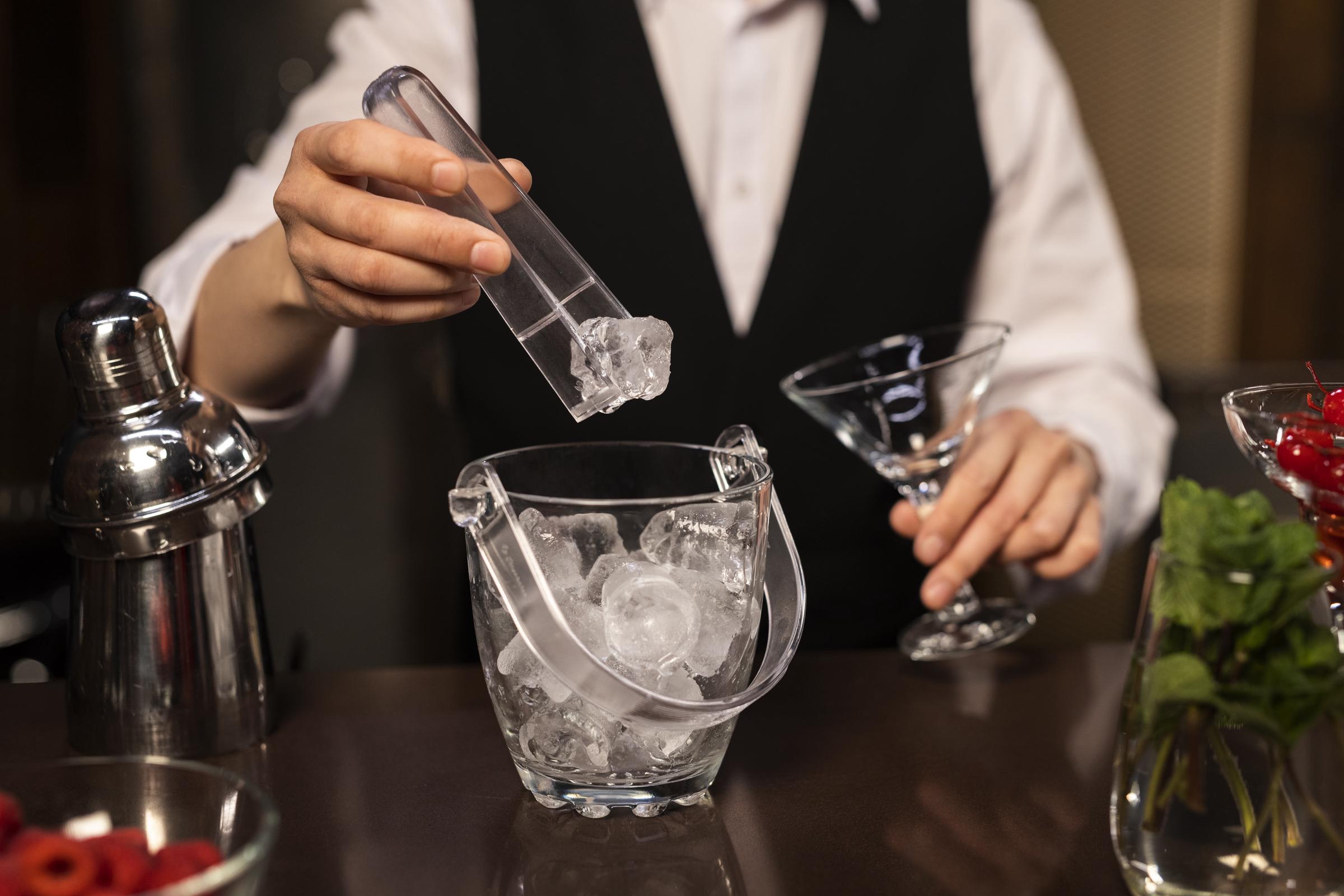 Un trabajador de un restaurante preparando una bebida con hielo | Fuente: Freepik