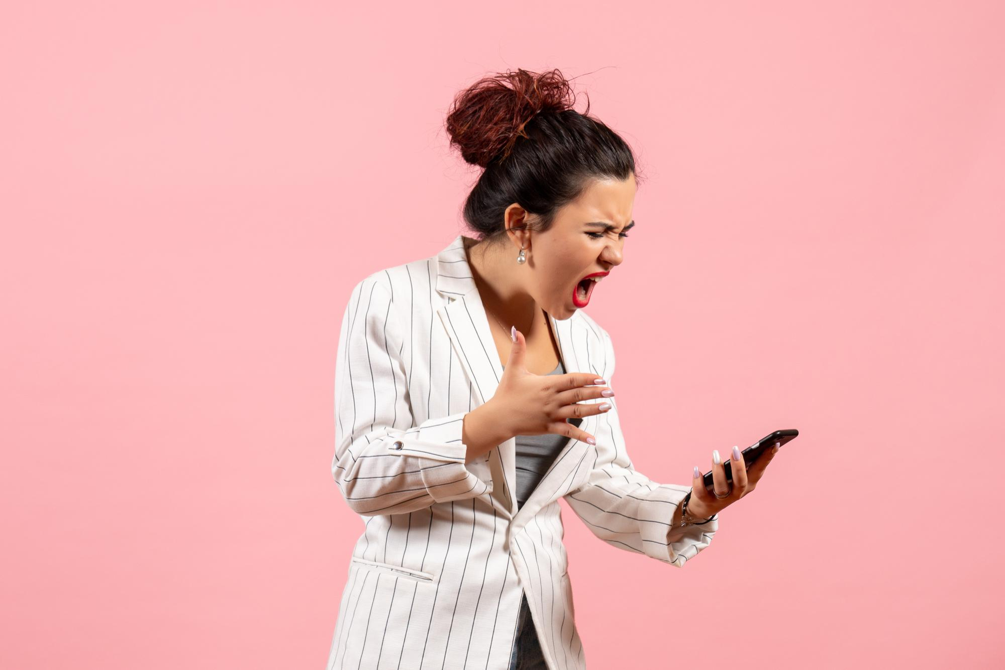 Una mujer enfadada mirando su teléfono | Fuente: Freepik