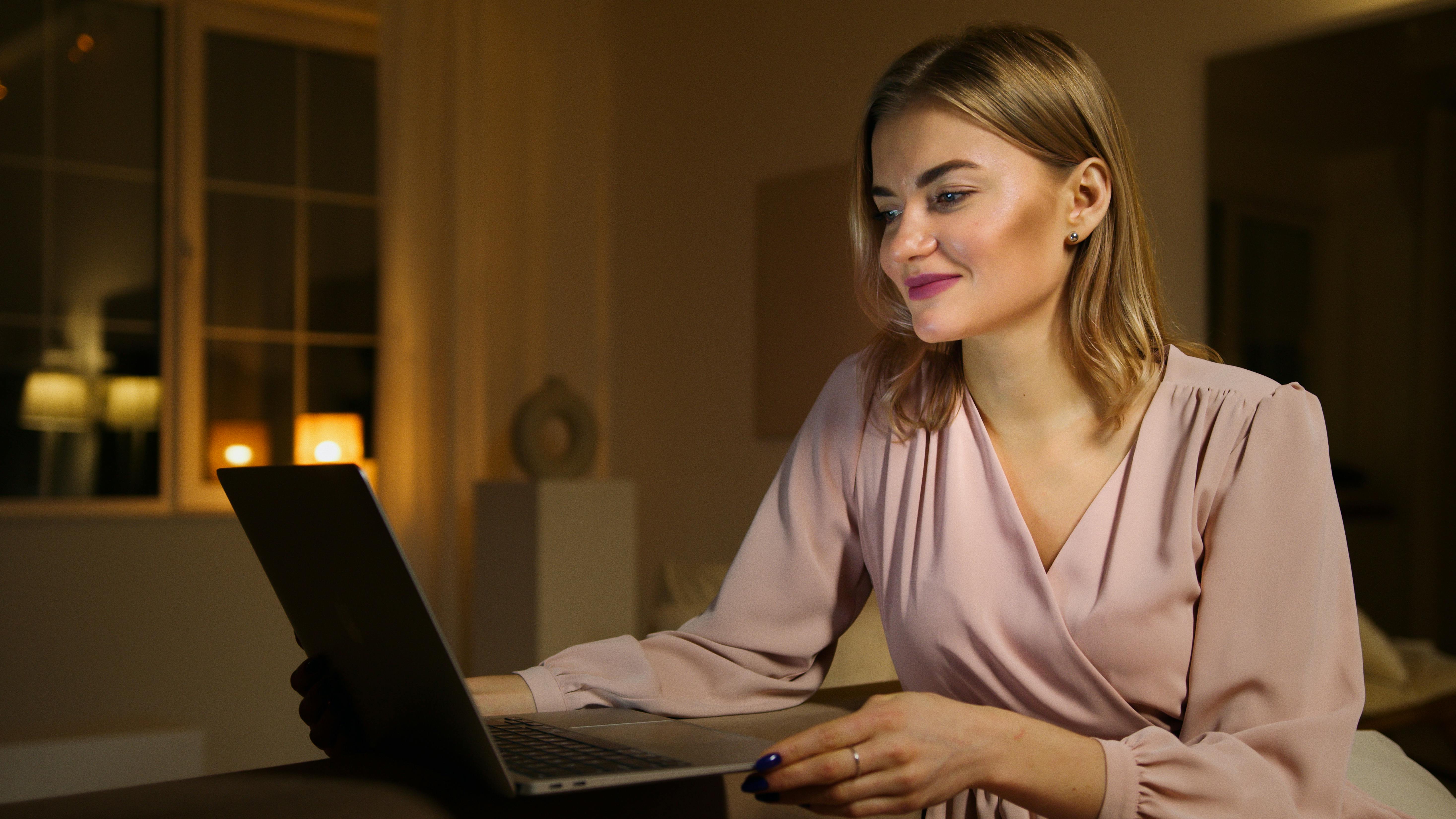 Una mujer mirando un portátil mientras sonríe | Fuente: Pexels