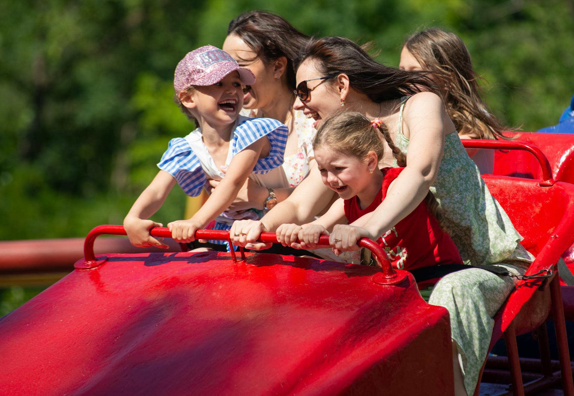 Donne e bambini sulle montagne russe di un parco divertimenti | Fonte: Pexels