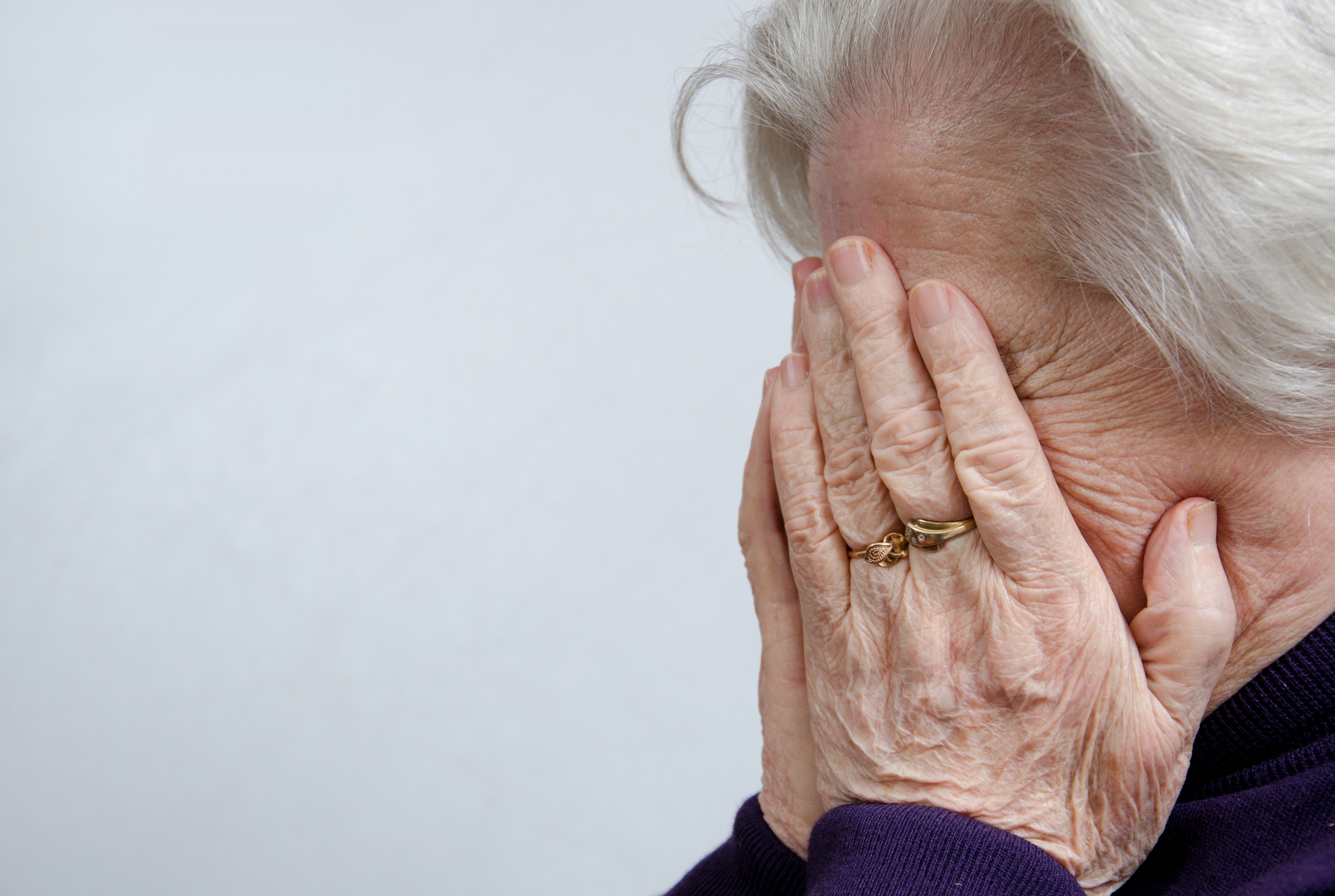 Una mujer de pelo blanco cubriéndose la cara con las manos | Foto: Shutterstock