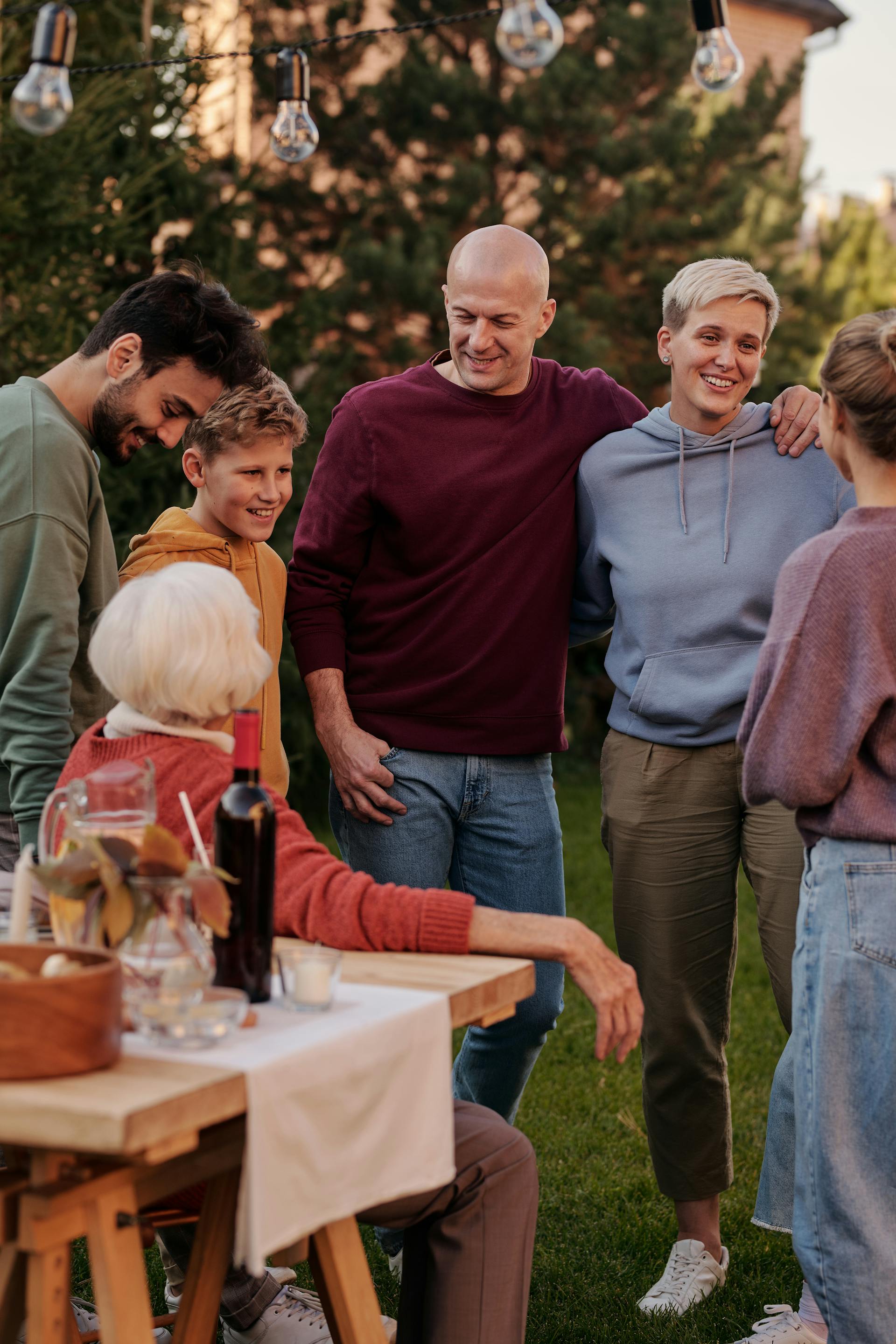 Gente de pie alrededor de una mesa en el exterior | Foto: Pexels