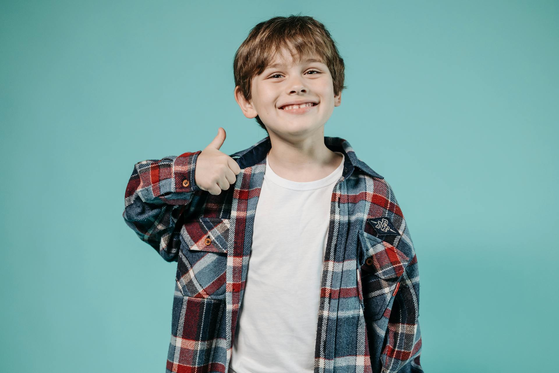 Un niño feliz haciendo la señal del pulgar hacia arriba | Fuente: Pexels