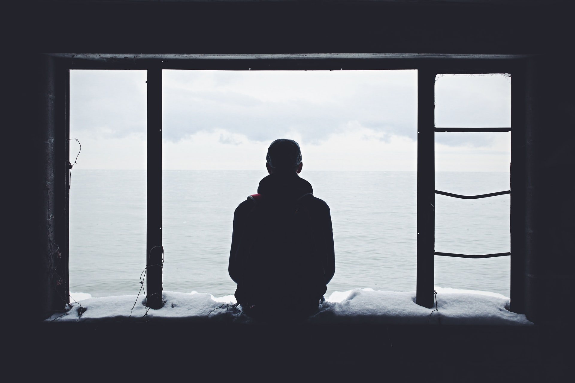 Hombre mirando el mar a través de un ventanal. | Foto: Unsplash