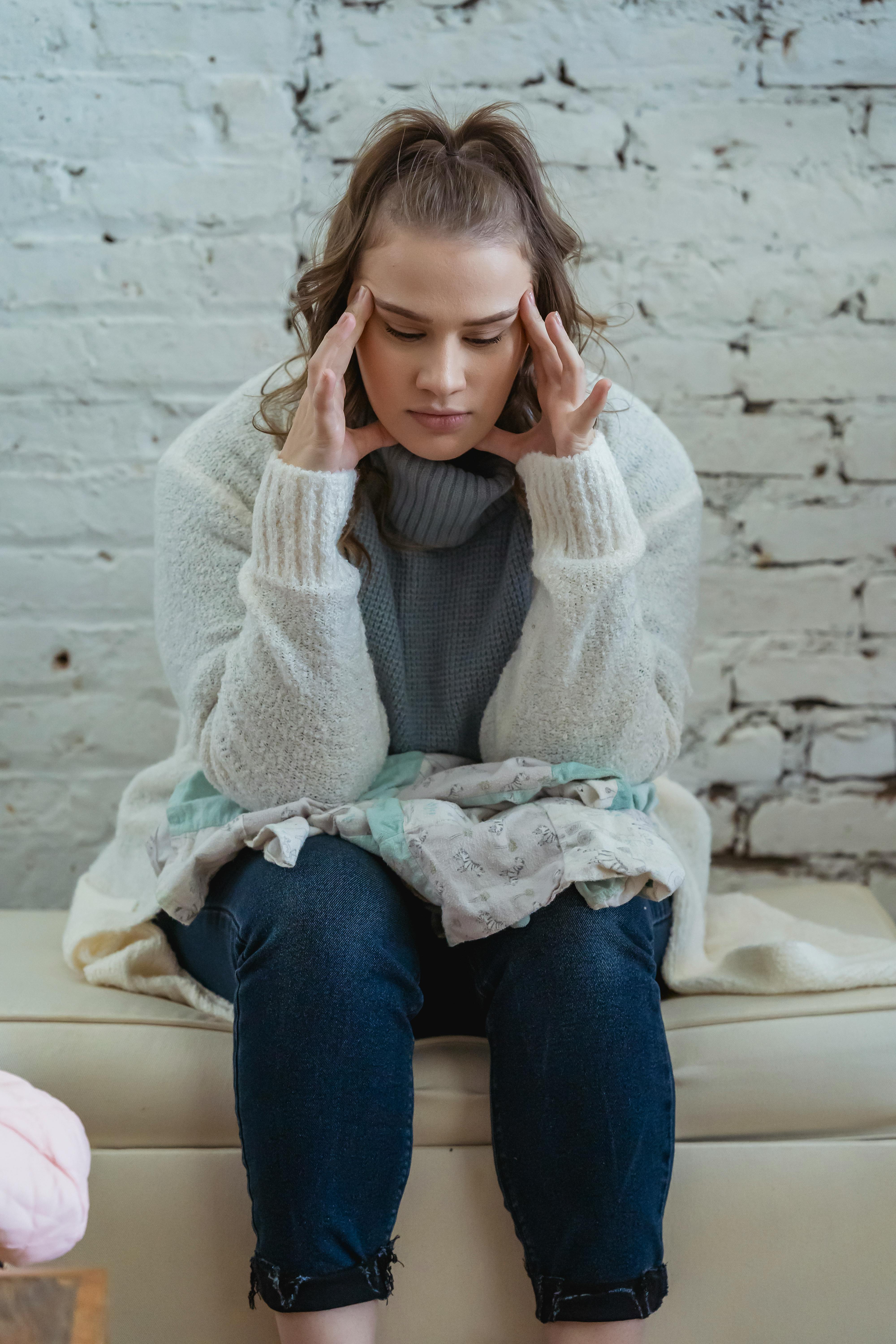 Mujer que parece enfadada mientras mira fijamente una prenda de ropa sobre su regazo | Fuente: Pexels