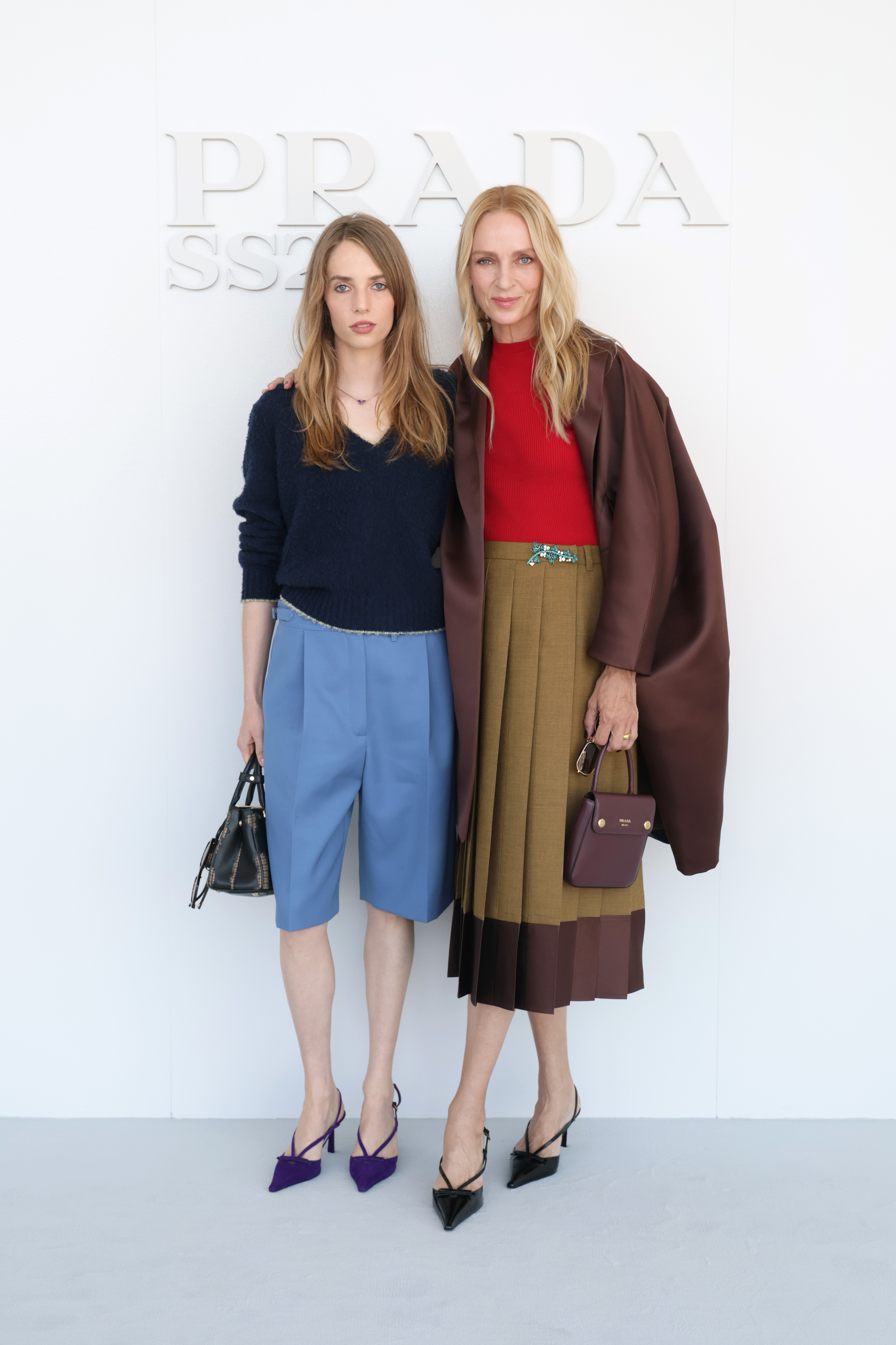 La pareja, madre e hija, posan juntas antes del desfile, mostrando al completo los pantalones cortos azul claro y los zapatos de tacón morados de Hawke, junto con la falda marrón en capas y el abrigo de Thurman. | Fuente: Getty Images