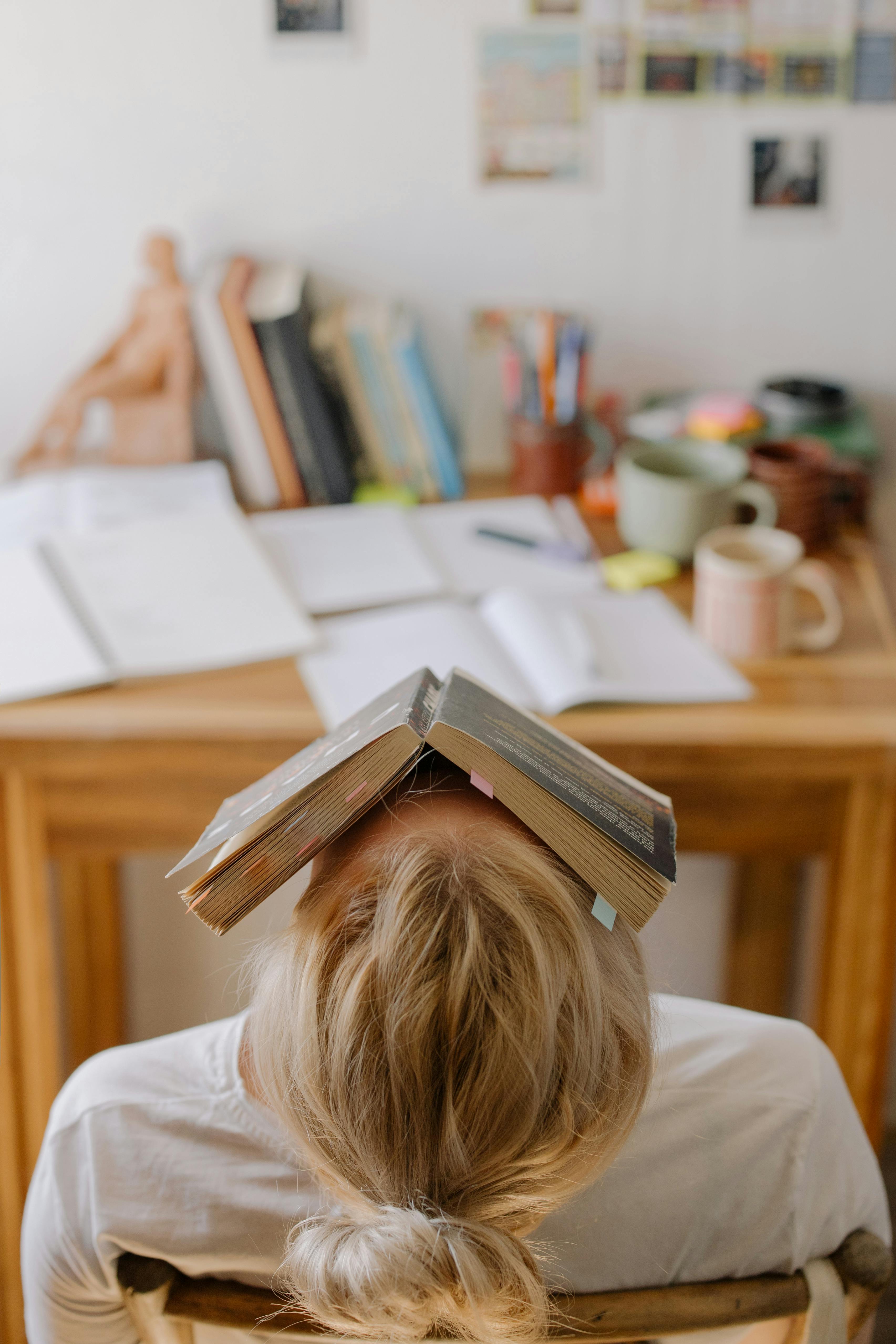 Una estudiante cansada con un libro | Fuente: Pexels