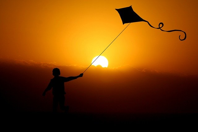 Niño elevando su cometa en una puesta de sol. | Foto: Pixabay