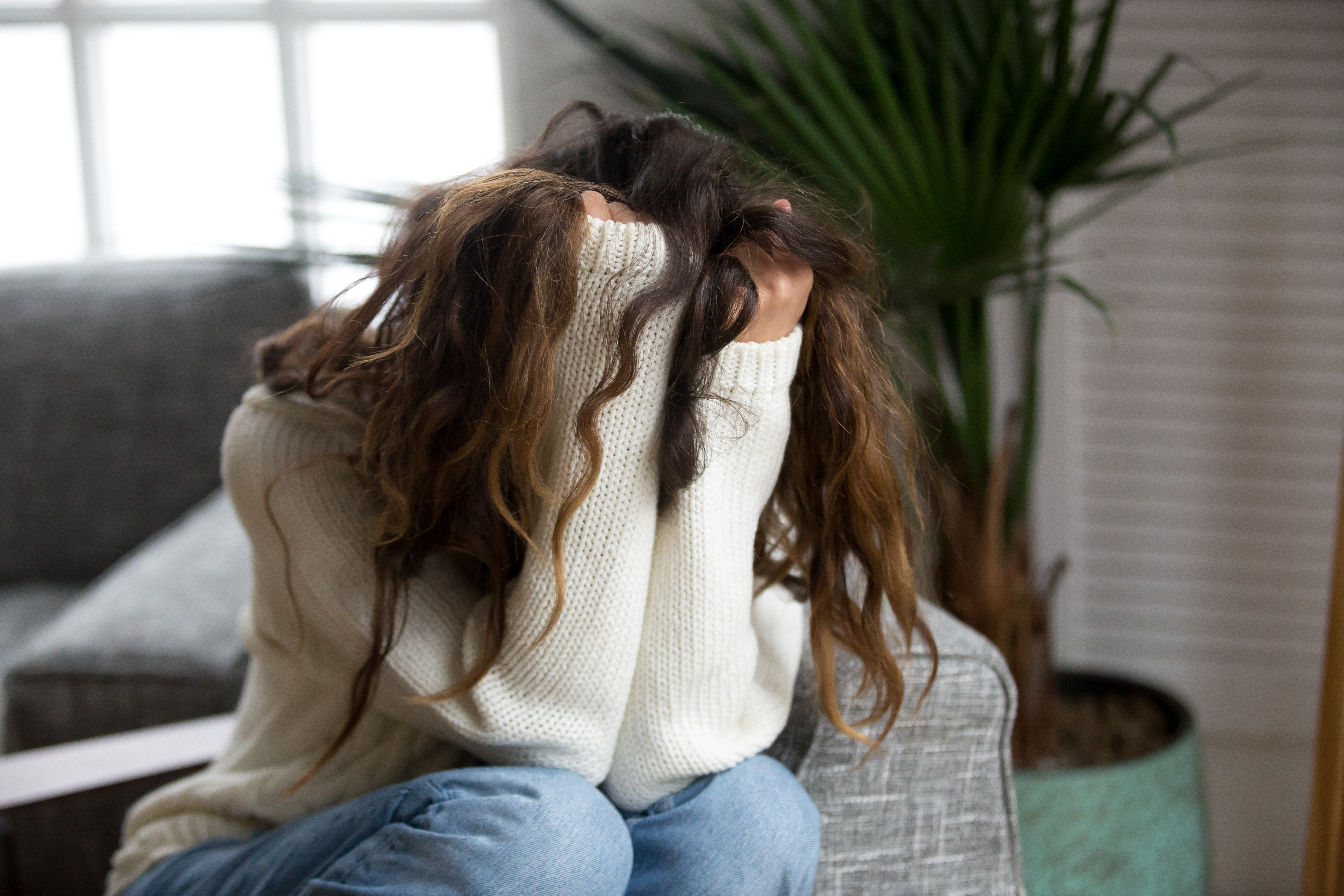 Una mujer deprimida ocultando su rostro con las manos | Fuente: Shutterstock