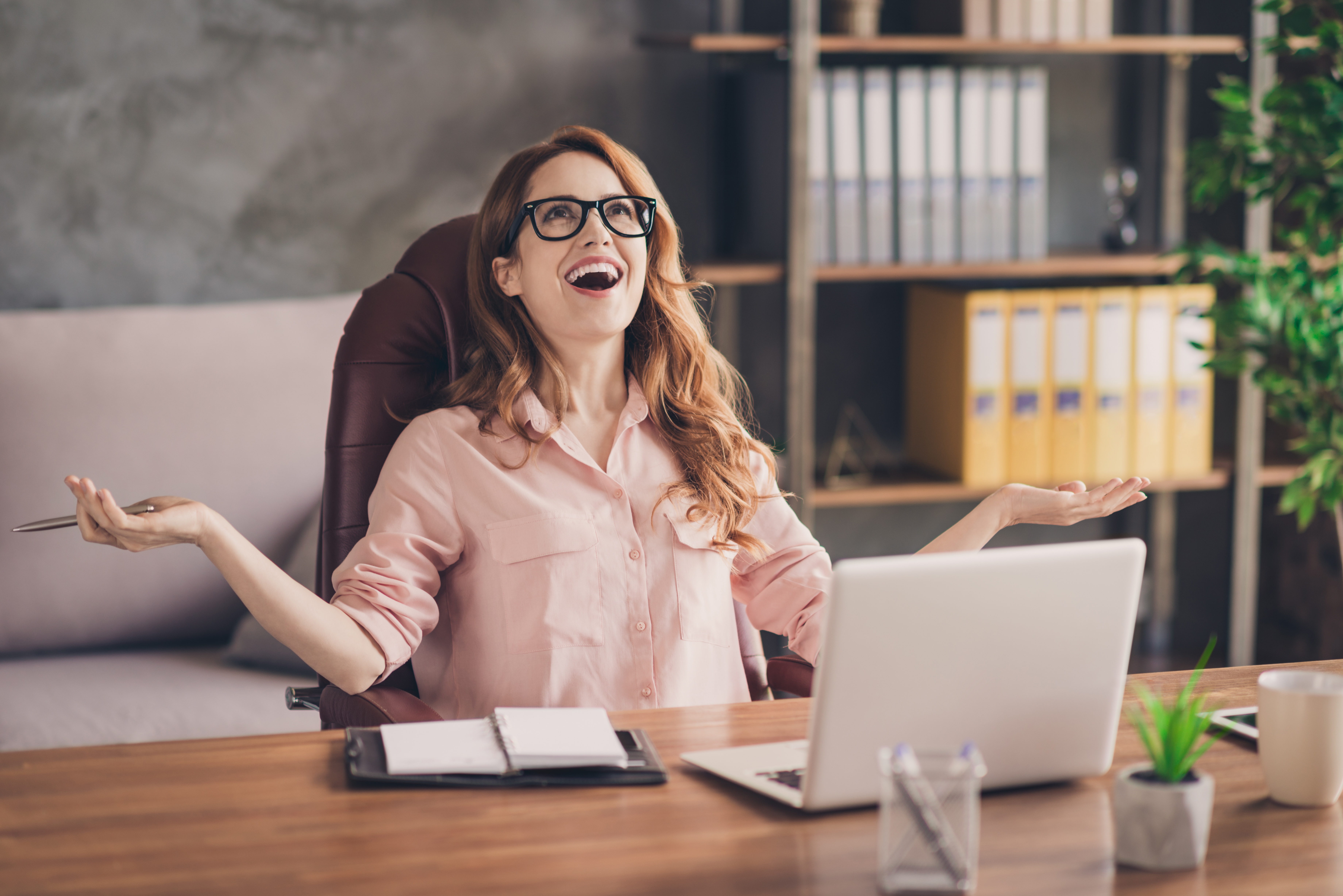 Close up photo beautiful she her business lady hand arm head raised up laugh laughter big salary income earnings genius startup notebook table sit office chair wearing specs formal-wear shirt | Fuente: Getty Images