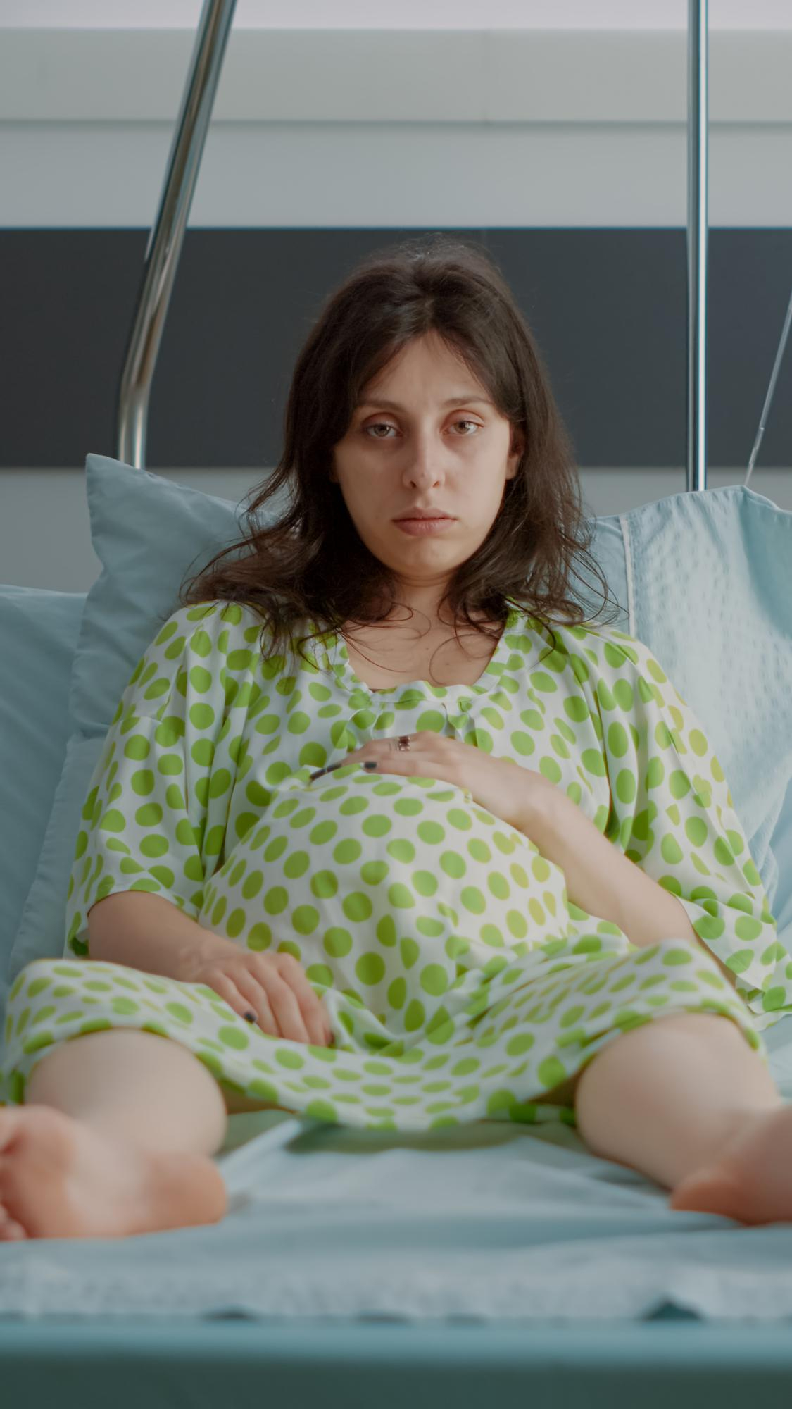 Una mujer embarazada infeliz tumbada en la cama de un hospital | Fuente: Freepik