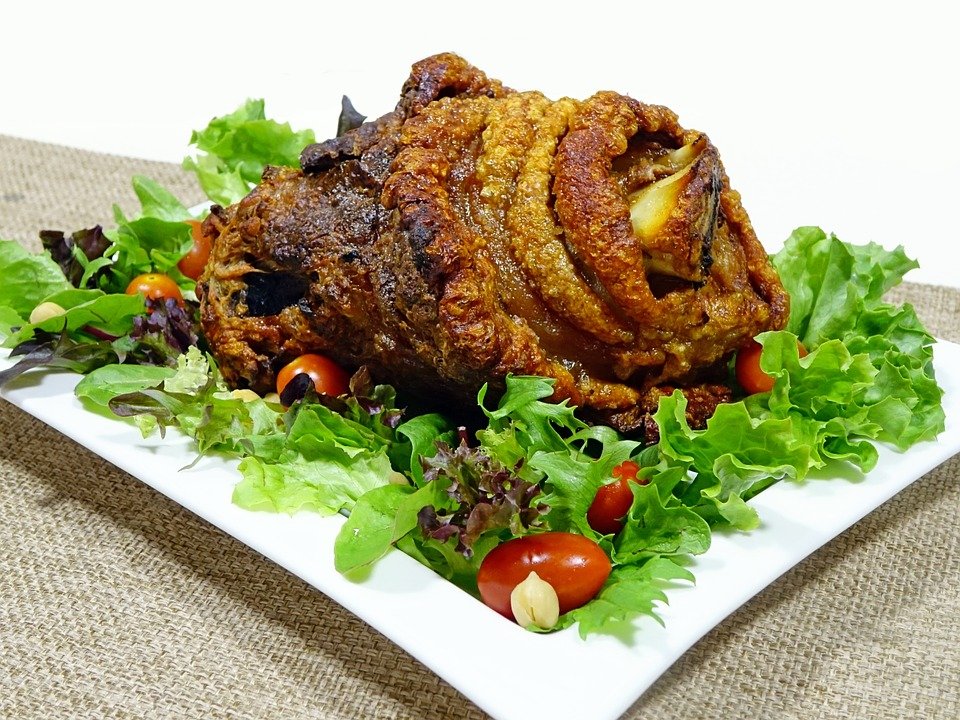 Pierna de cerdo asada colocada sobre una cama de lechuga y vegetales variados. | Foto: Pixabay