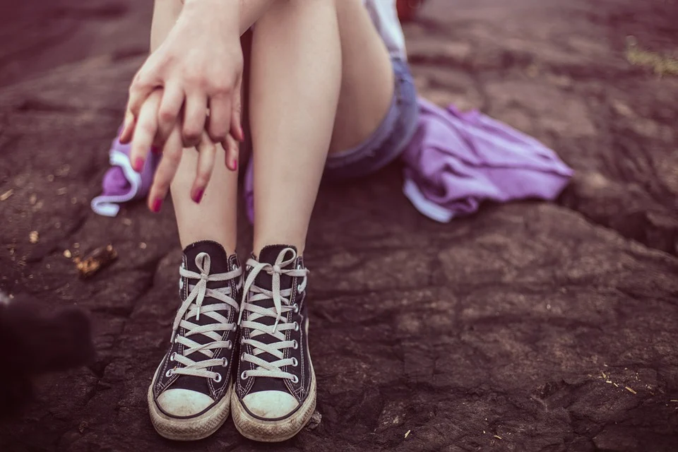 Mujer usando zapatos tipo 'converse' mientras está sentada en el suelo. | Foto: Pixabay