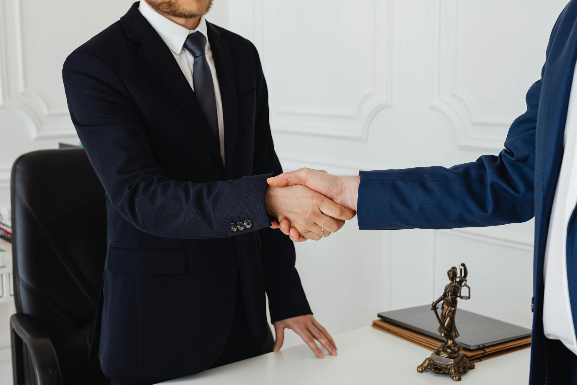 Primer plano de dos hombres dándose la mano en un ambiente formal | Fuente: Pexels