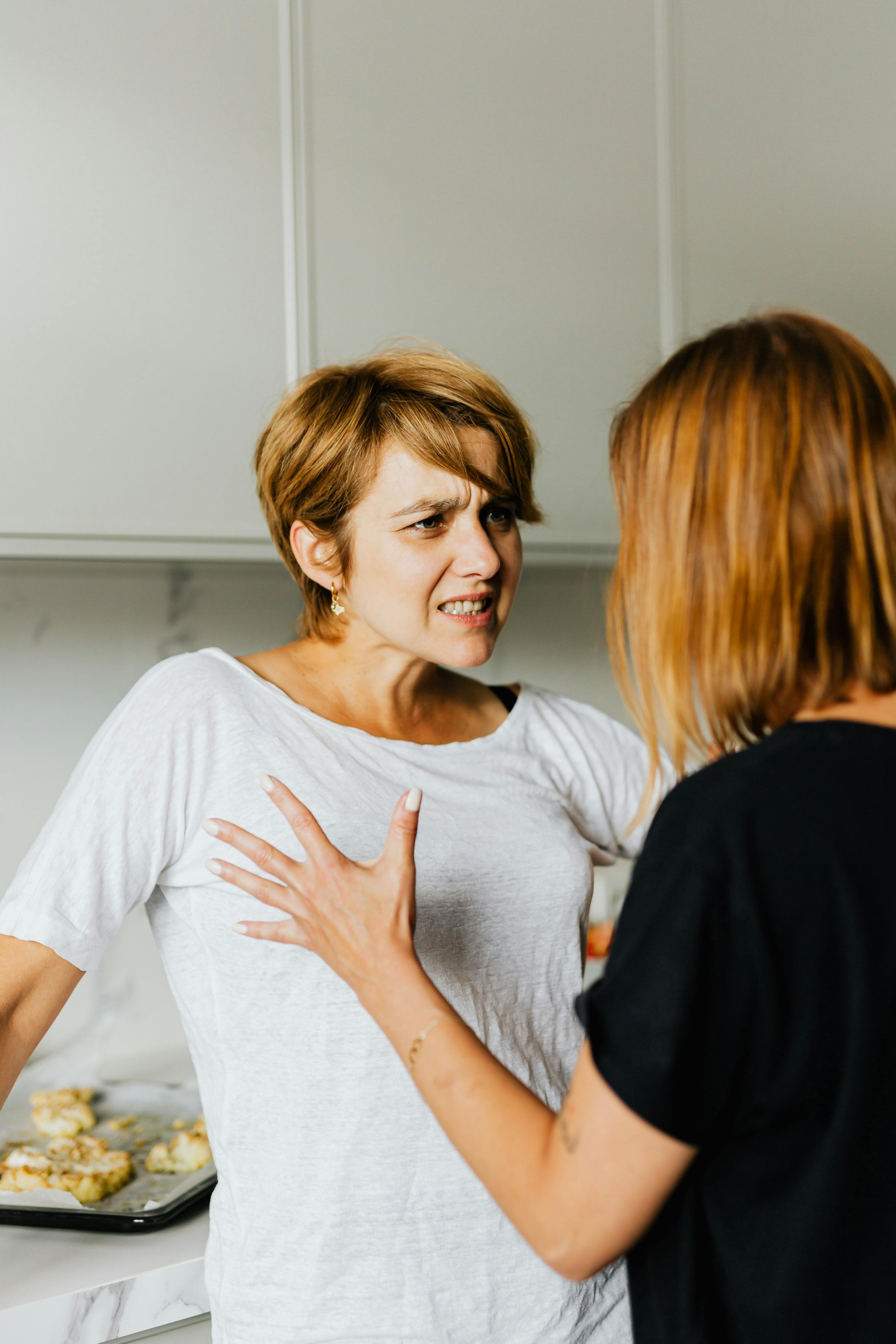 Una mujer con cara de disgusto mientras escucha hablar a otra | Foto: Pexels