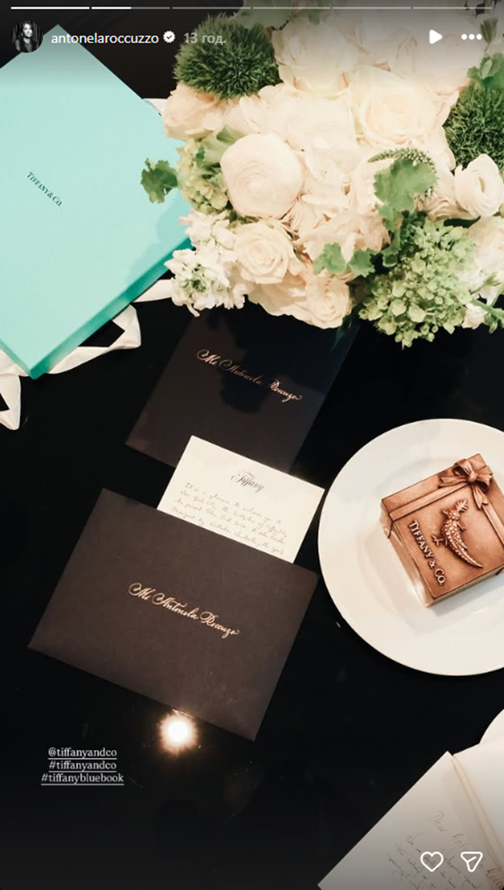 Una tarjeta dentro de un sobre negro encima de una mesa decorada con rosas blancas | Fuente: Instagram Stories/antonelaroccuzzo