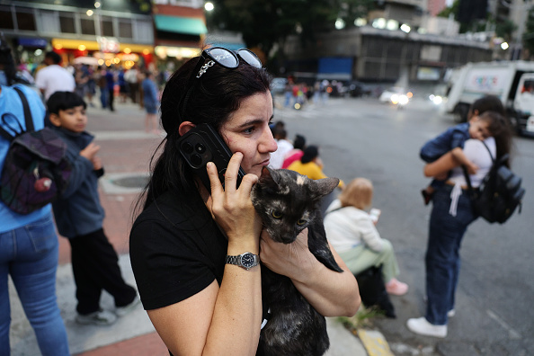 Una mujer evacuada, que lleva un gato en brazos, habla por teléfono mientras espera en el complejo urbanístico Parque Central, en Caracas, Venezuela, tras el terremoto de magnitud 7,2 que sacudió el país y otras regiones del Caribe el 24 de junio de 2026.