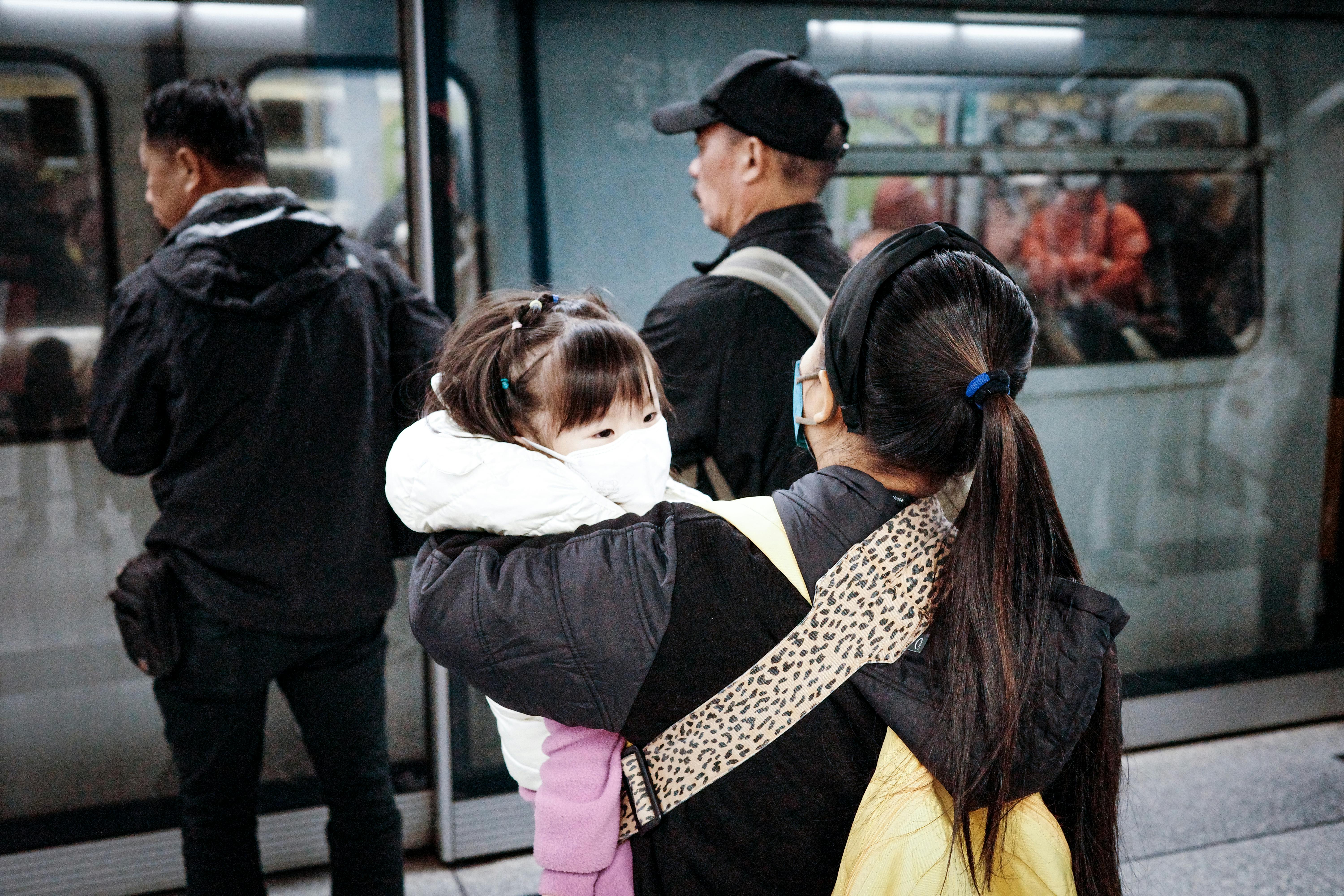 Una mujer con un niño en brazos a punto de subir al metro | Foto: Pexels