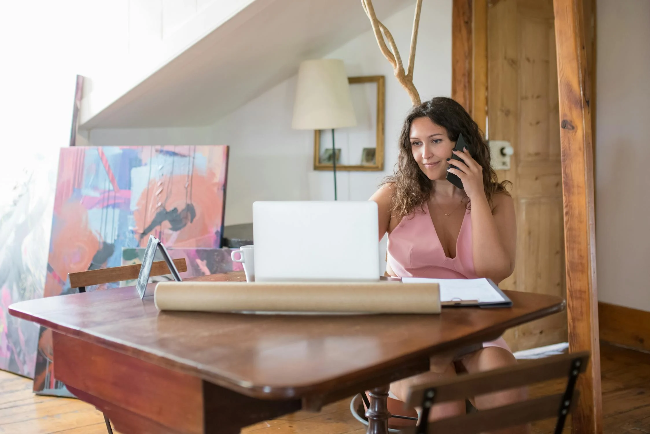 Una mujer hablando por teléfono y mirando su portátil | Fuente: Pexels