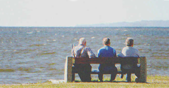 Tres hombres mayores sentados en un banco junto al mar | Fuente: Shutterstock