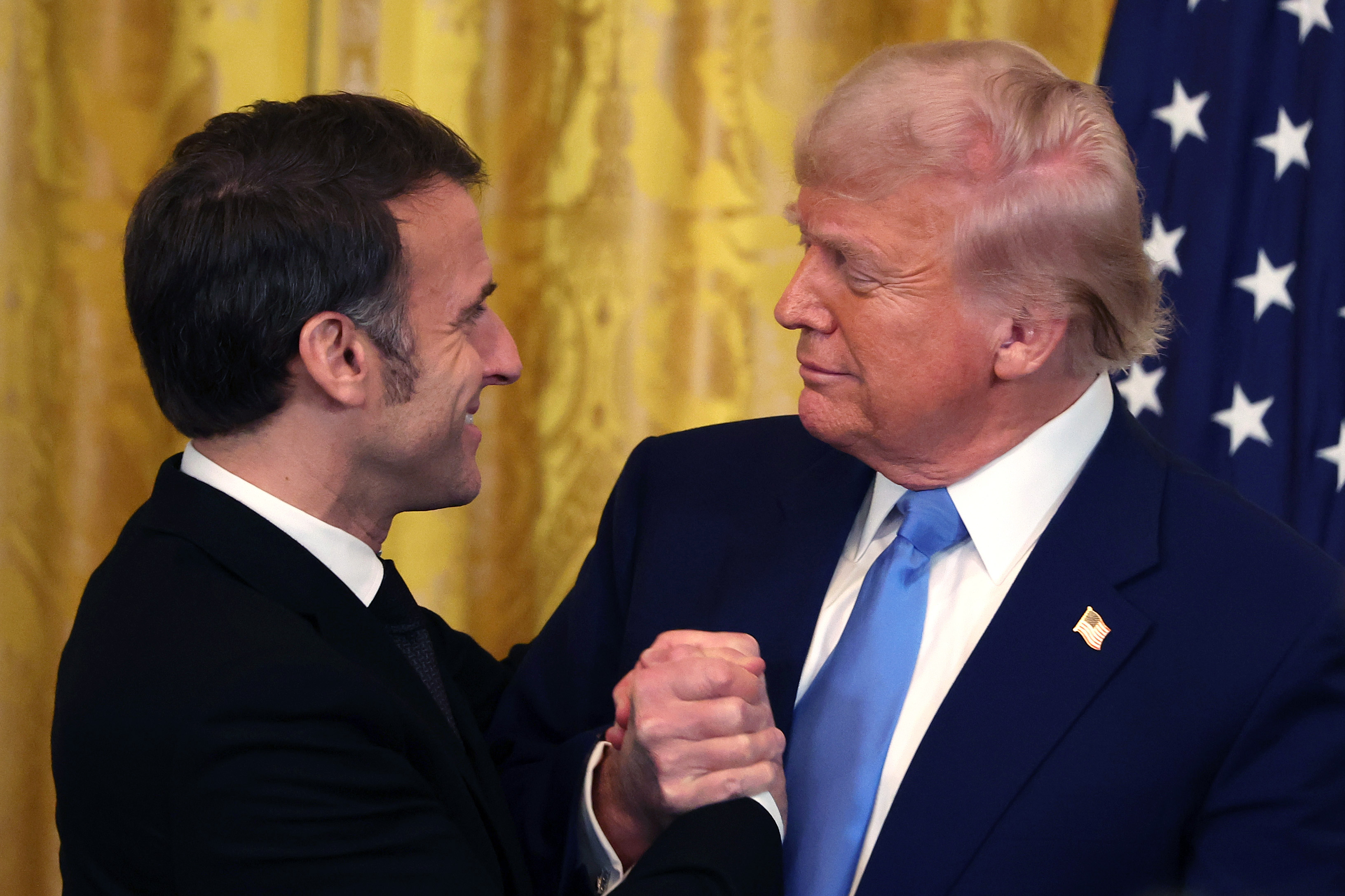 Emmanuel Macron y Donald Trump se dan la mano y se abrazan en la Sala Este de la Casa Blanca en Washington, D.C., el 24 de febrero de 2025. | Fuente: Getty Images