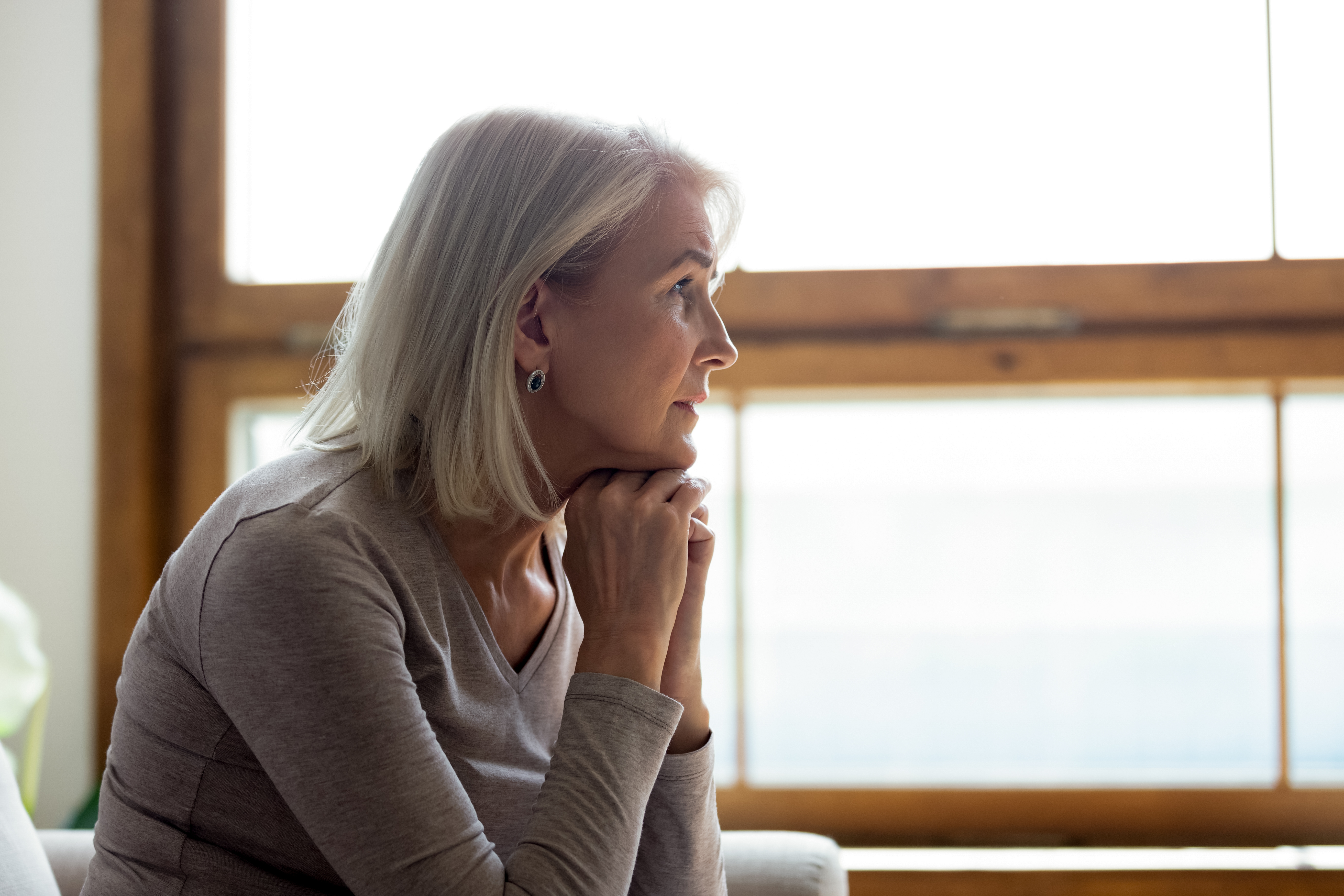 Mujer mayor mirando por la ventana | Foto: Shutterstock