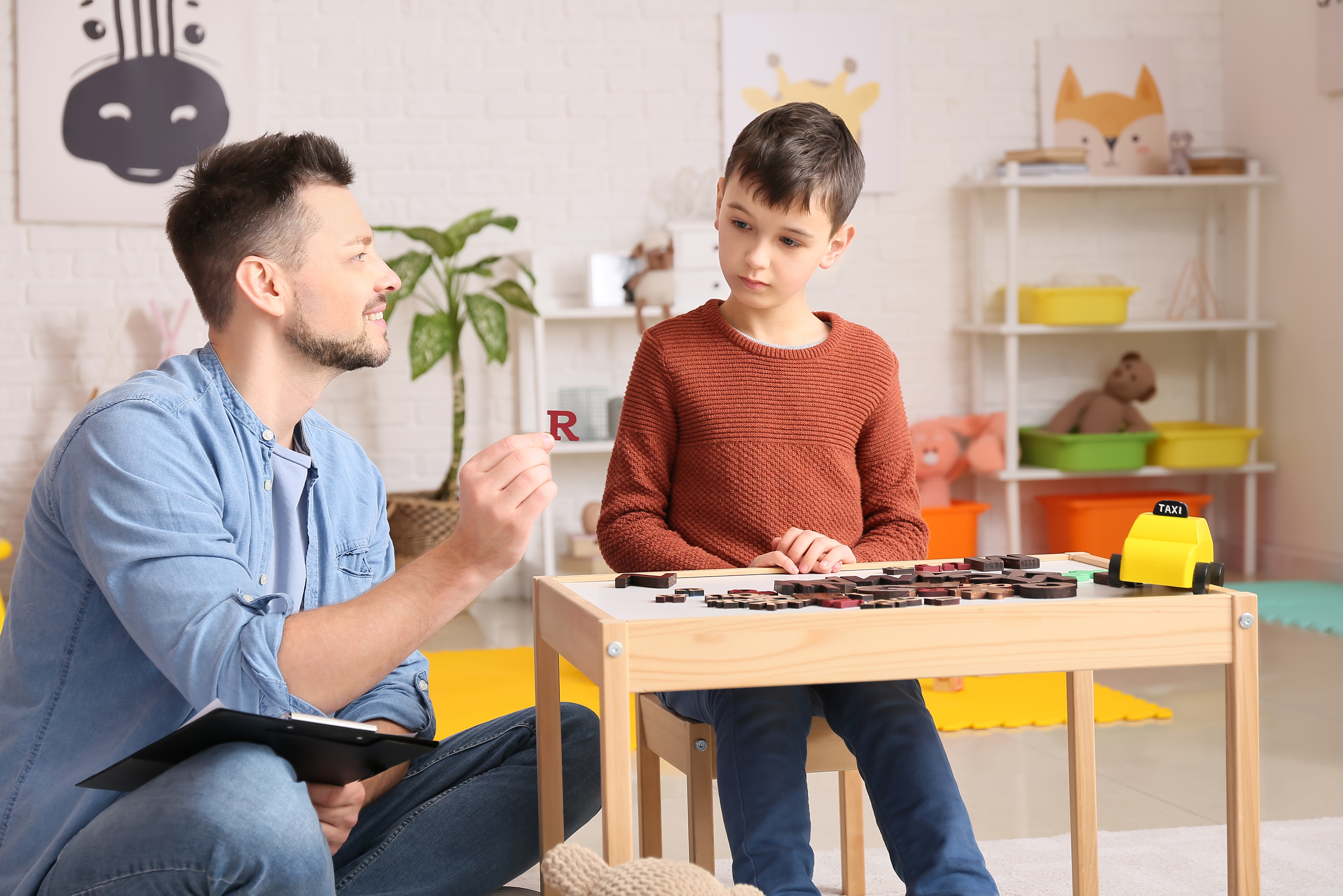 Psicólogo masculino trabajando con un niño en la consulta. | Fuente: Shutterstock