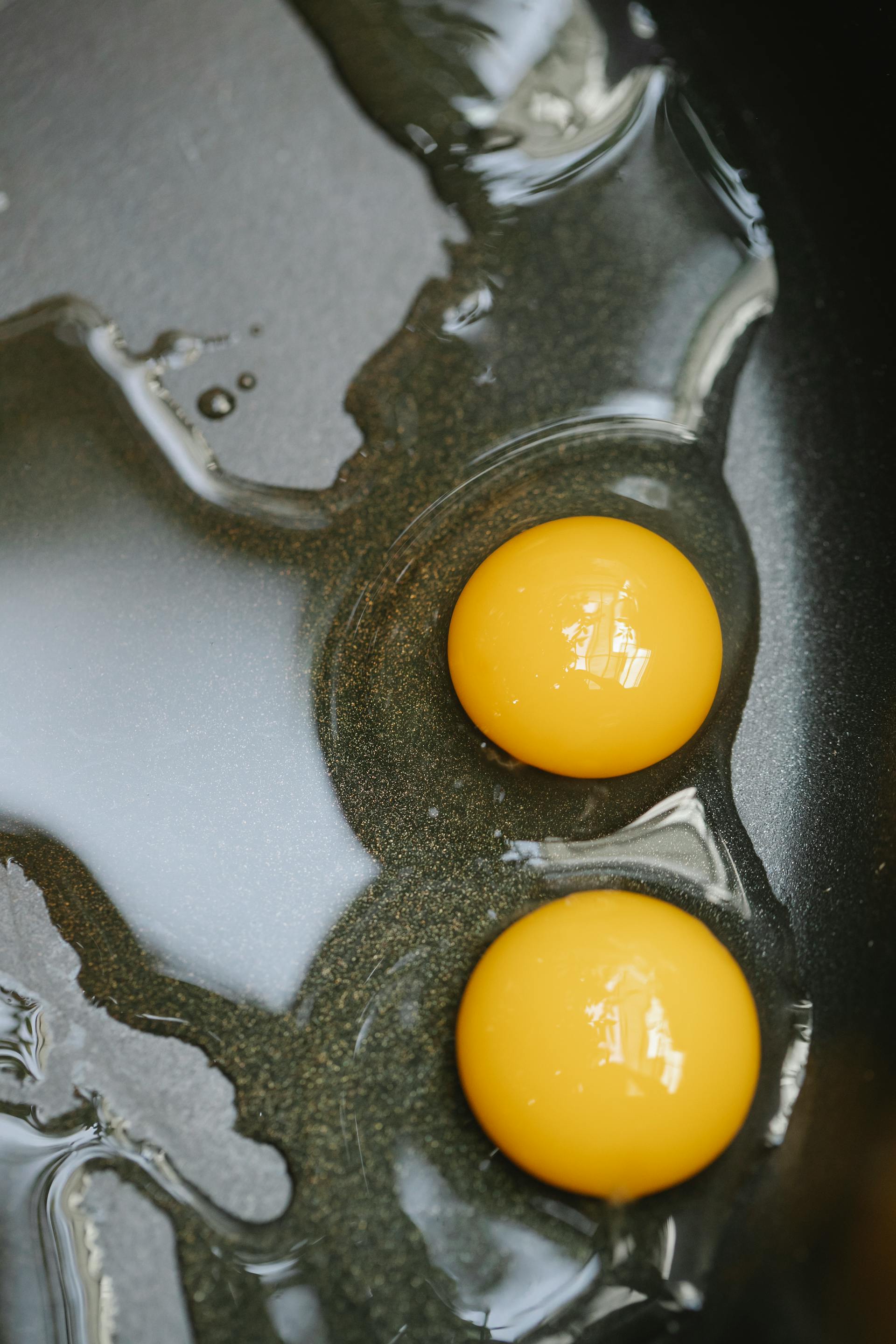 Primer plano de huevos friéndose en una sartén negra | Fuente: Pexels