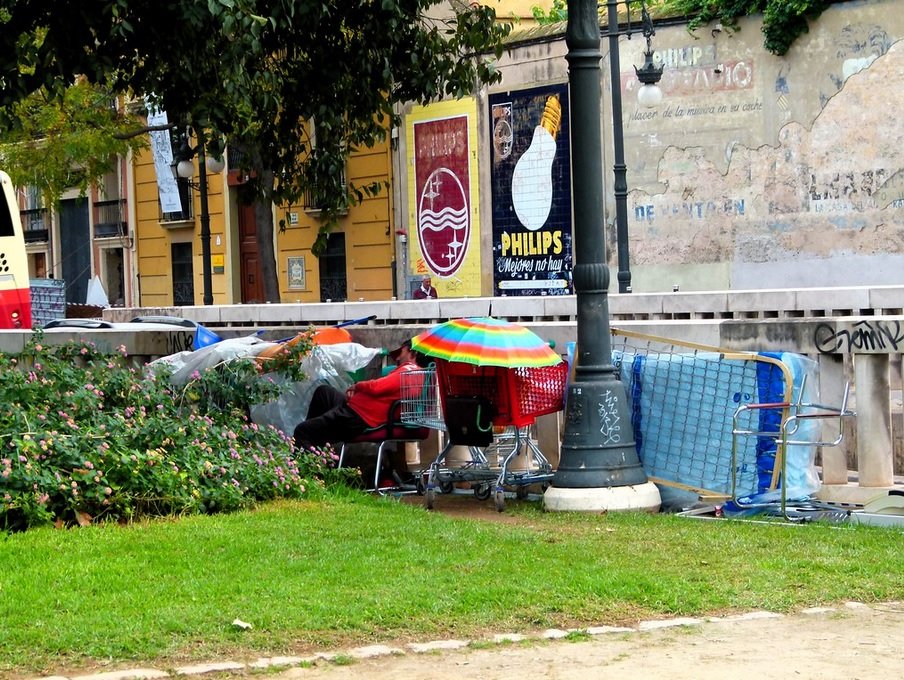 Persona sin hogar con sus objetos aglomerados en el área de un parque. | Foto: Flickr