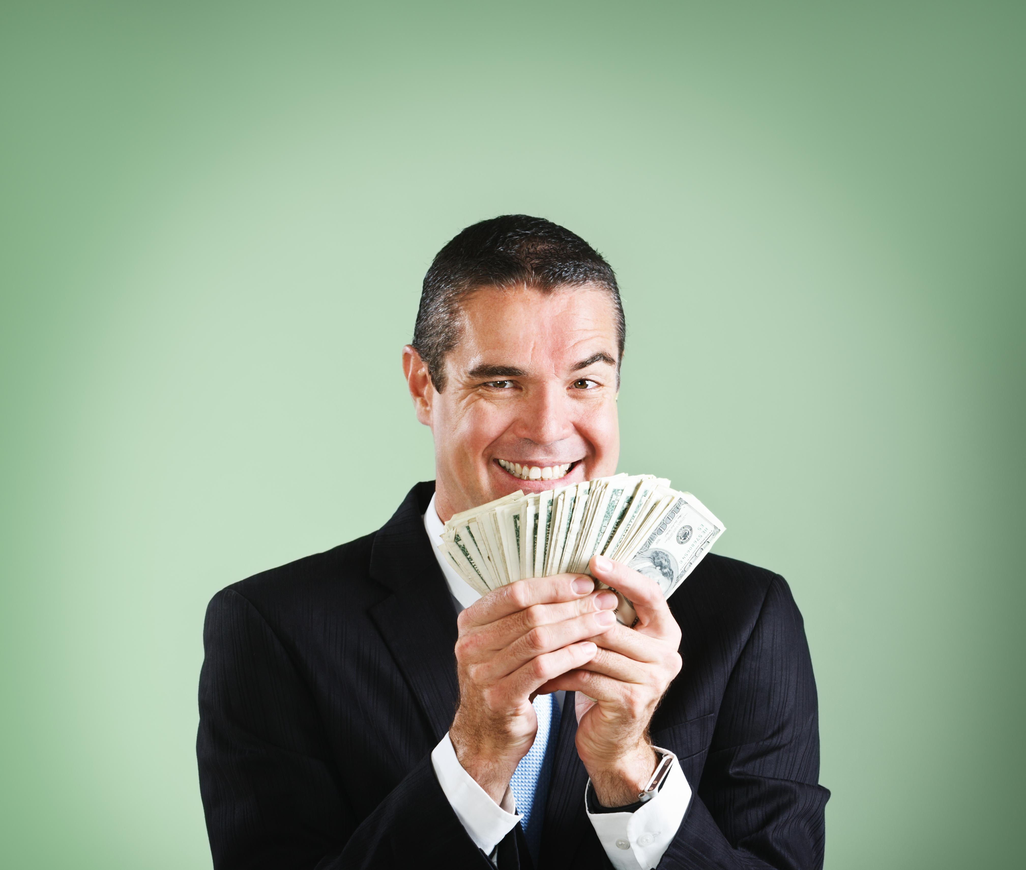 Un hombre de negocios sonríe, regodeándose con un puñado de dólares | Foto: Getty Images