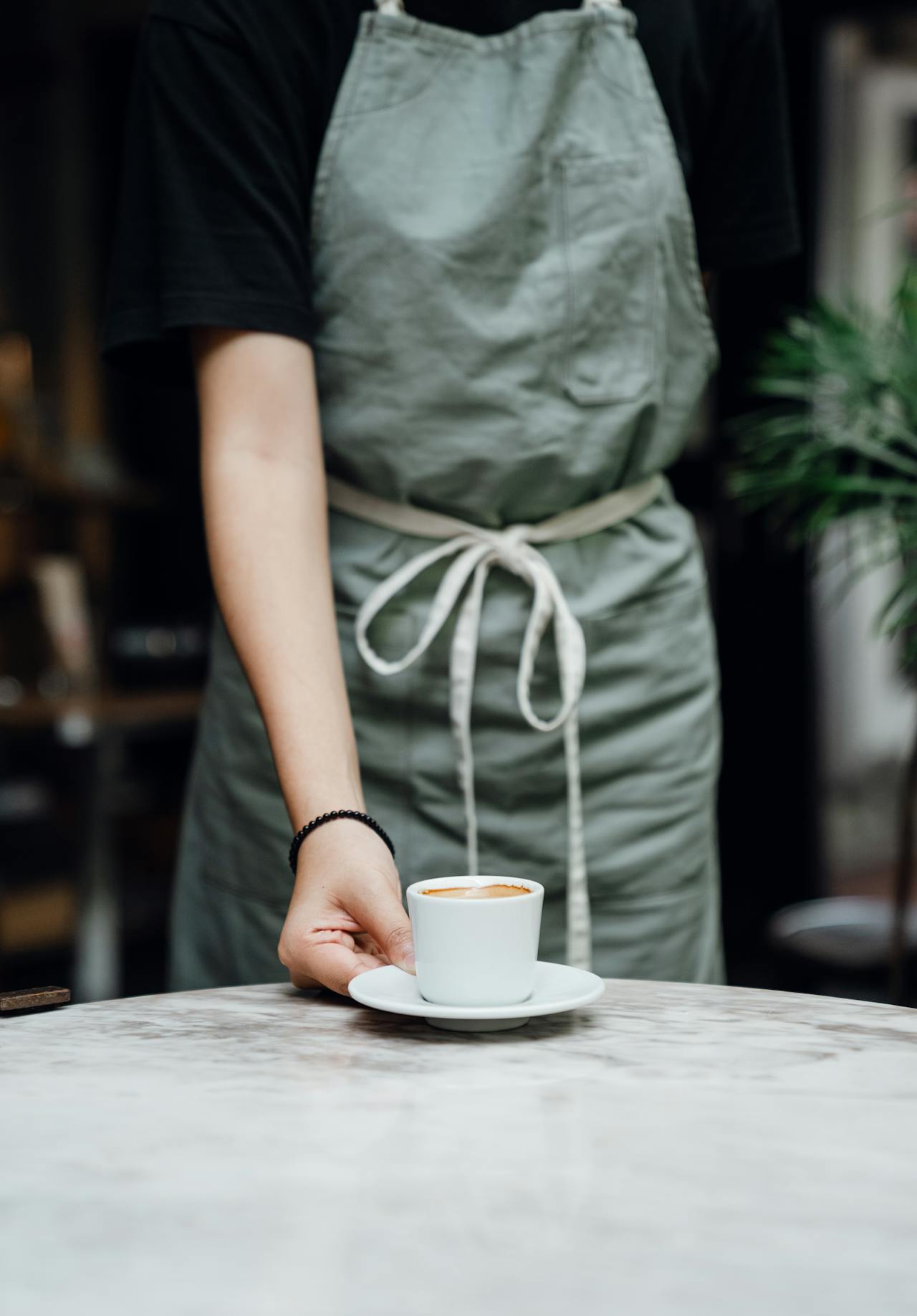 Una camarera colocando una taza de café sobre la mesa | Fuente: Pexels