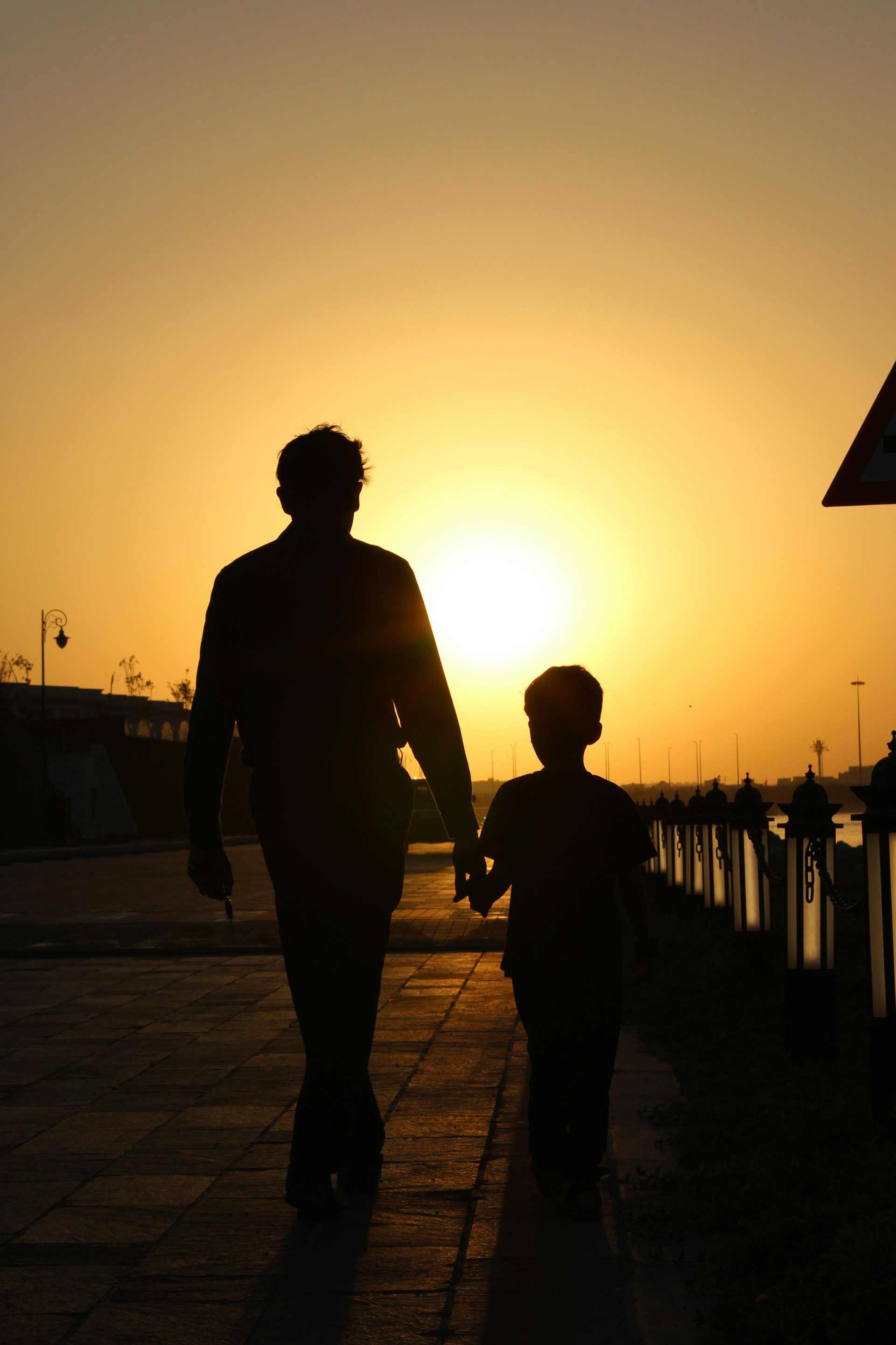 Silueta de un padre y su hijo caminando por la calle | Fuente: Unsplash