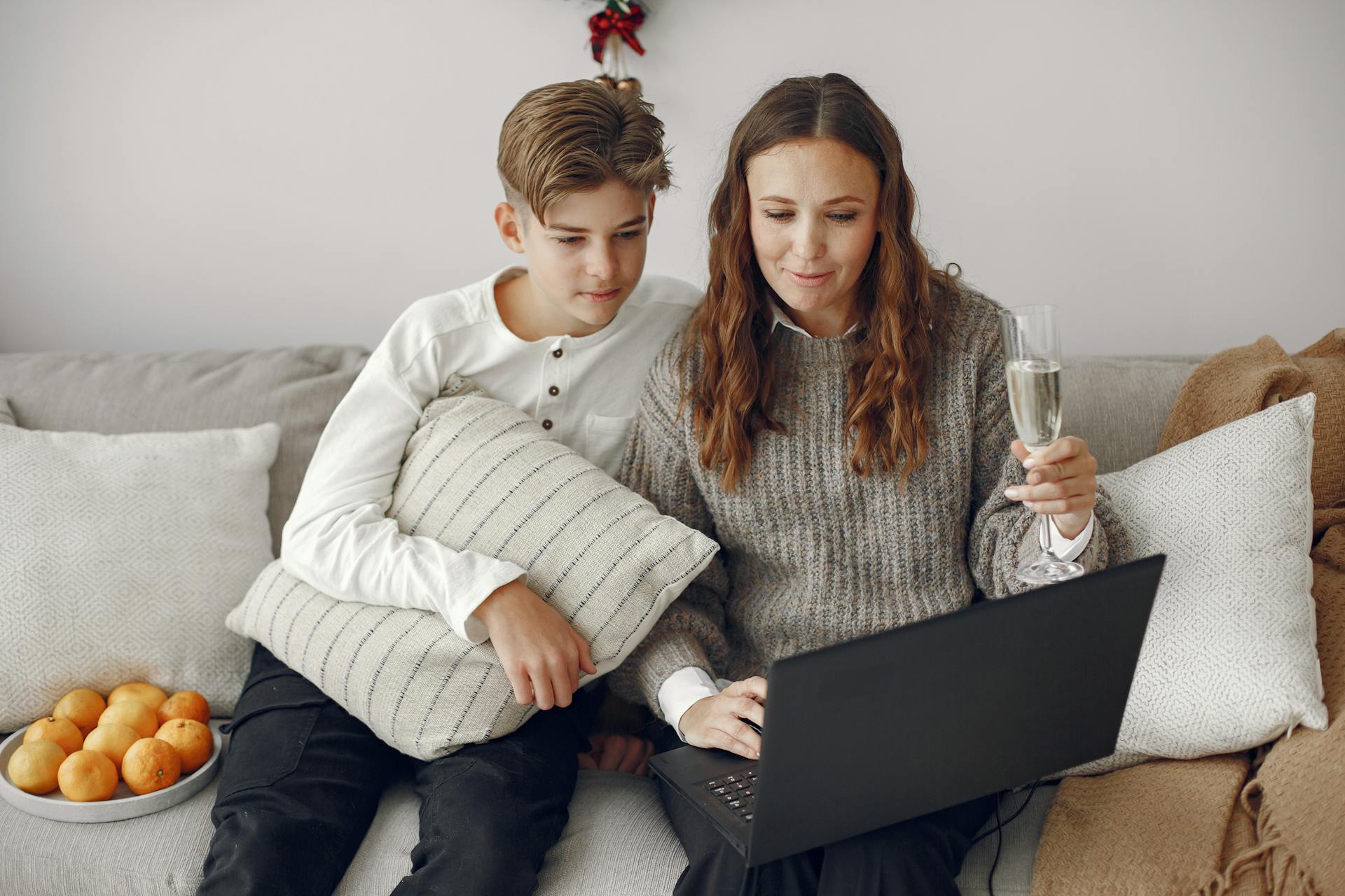 Un dúo madre-hijo sentado en un sofá y utilizando un ordenador portátil | Fuente: Pexels