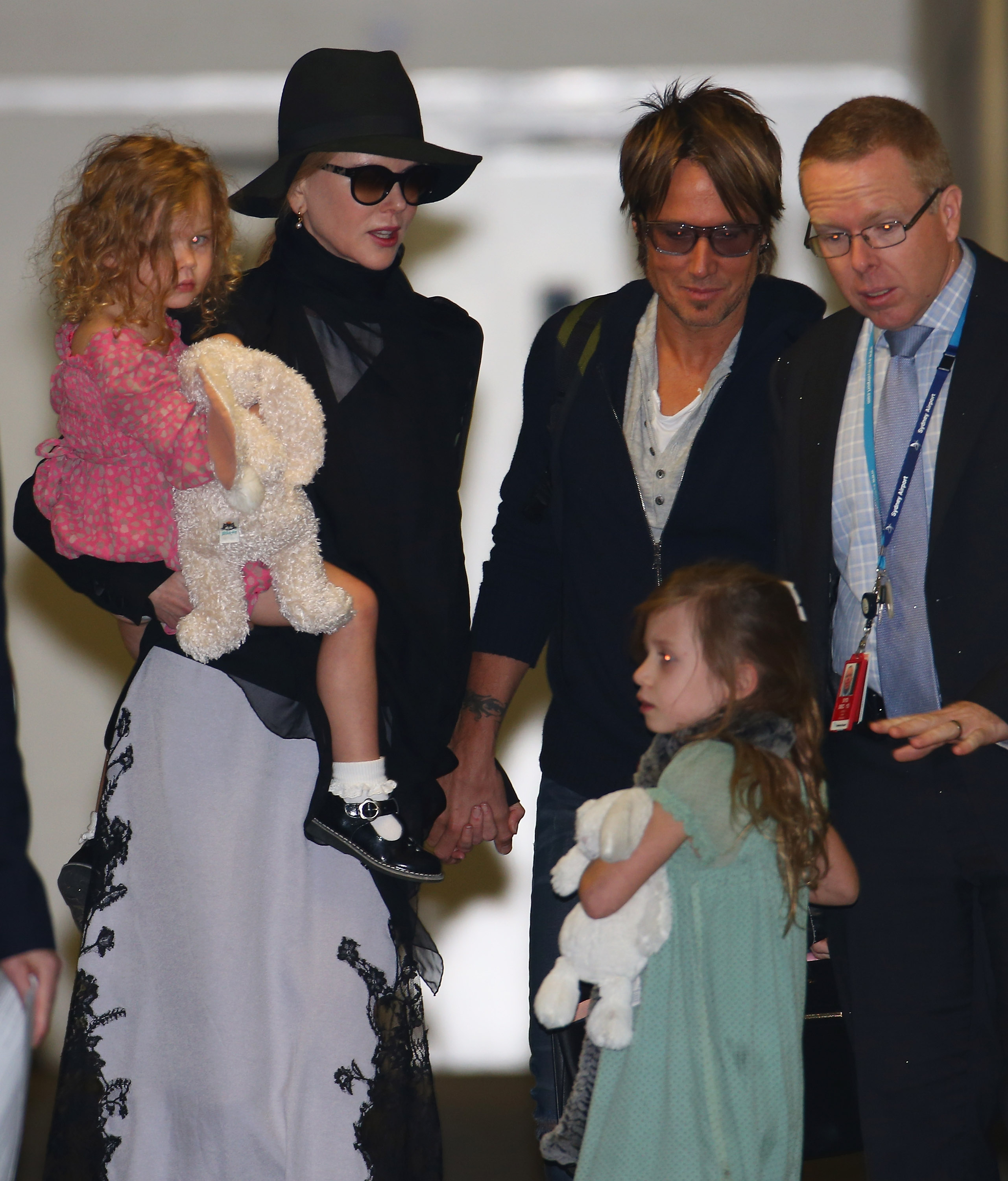 Nicole Kidman lleva en brazos a Faith Margaret, de tres años, mientras que Keith Urban va de la mano de Sunday Rose, de cinco, en el Aeropuerto Internacional de Los Ángeles en enero de 2014. Las dos niñas se llevaron sus peluches favoritos para el viaje en familia. | Fuente: Getty Images