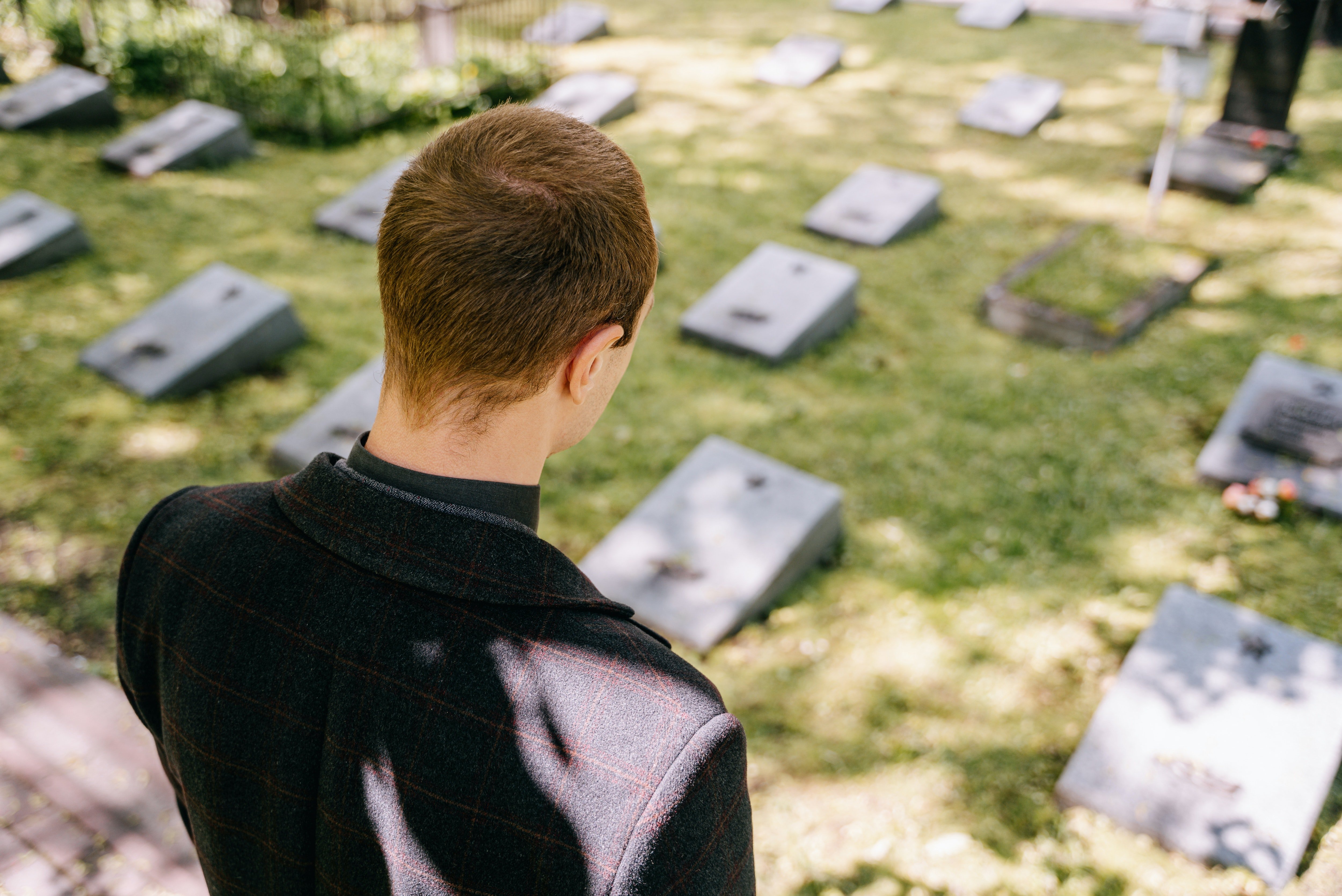 Joven parado frente a unas tumbas. | Foto: Pexels