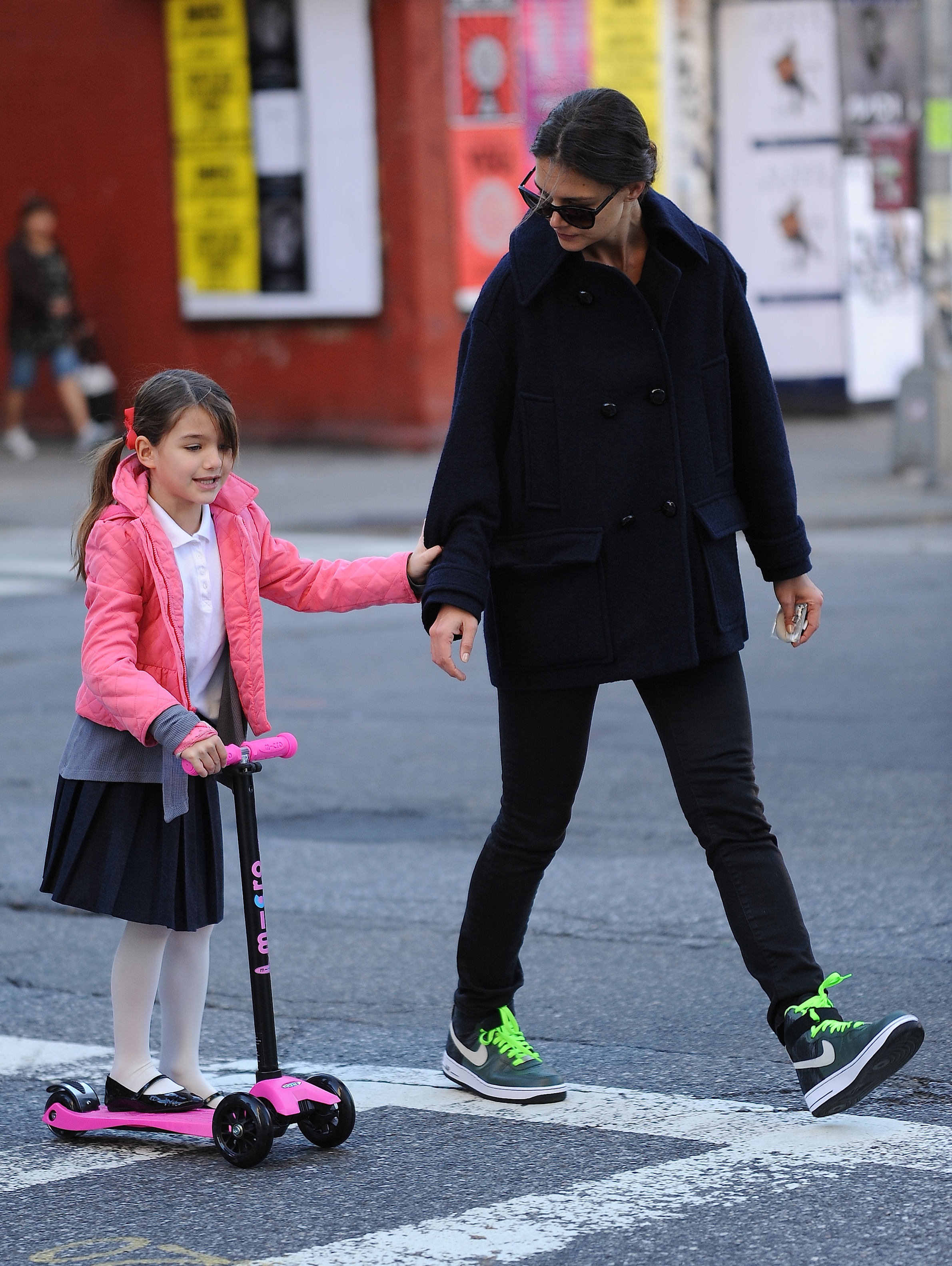 Katie Holmes ayudando a Suri Cruise a montar en patinete en Nueva York, el 8 de octubre de 2013 | Foto: Getty Images