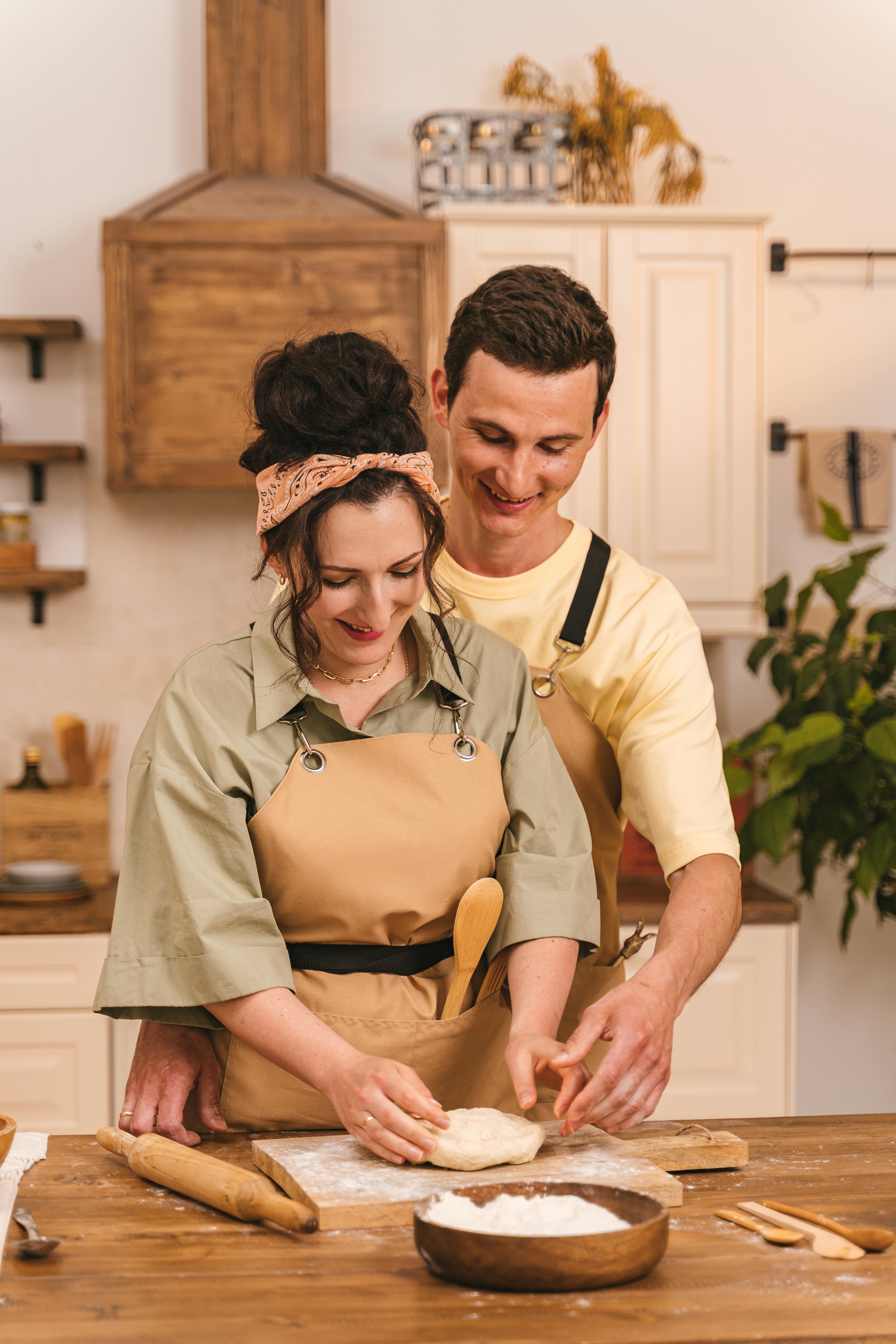 Un hombre sonriente mirando a su esposa mientras cocina | Fuente: Pexels