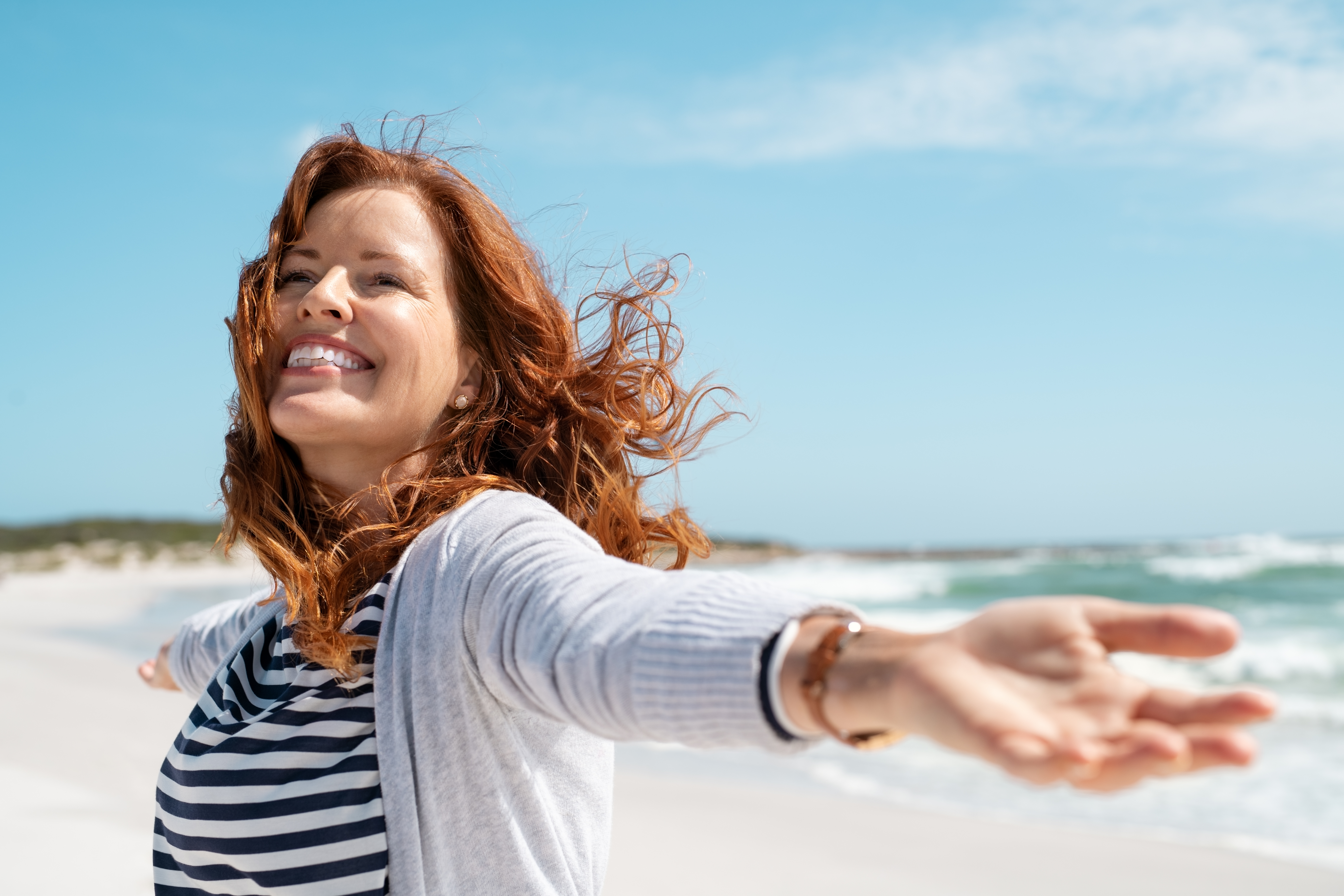 Una mujer feliz en la orilla del mar | Fuente: Shutterstock