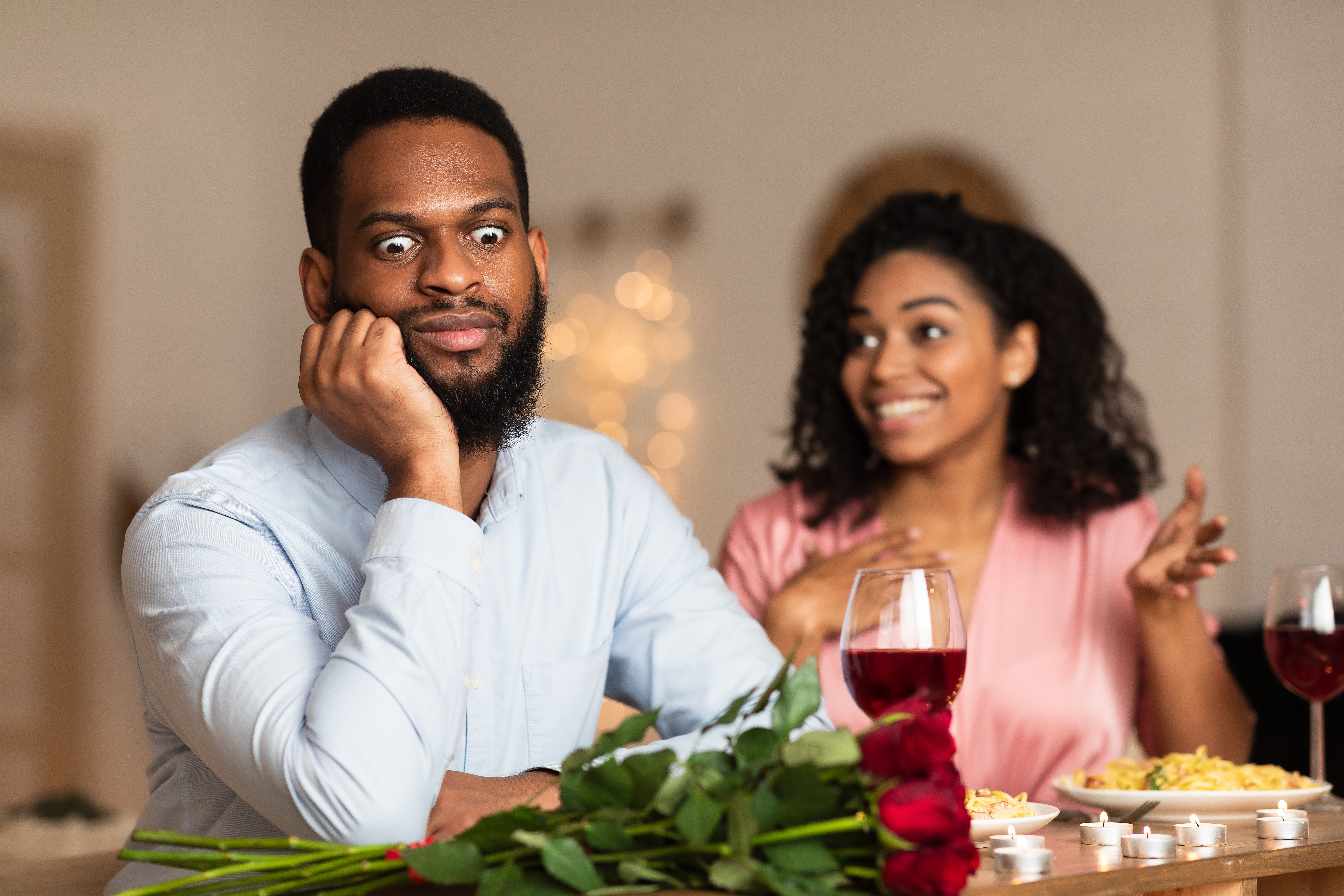 Hombre negro insatisfecho y conmocionado escuchando hablar a una mujer emocionada y excitada | Fuente: Shutterstock