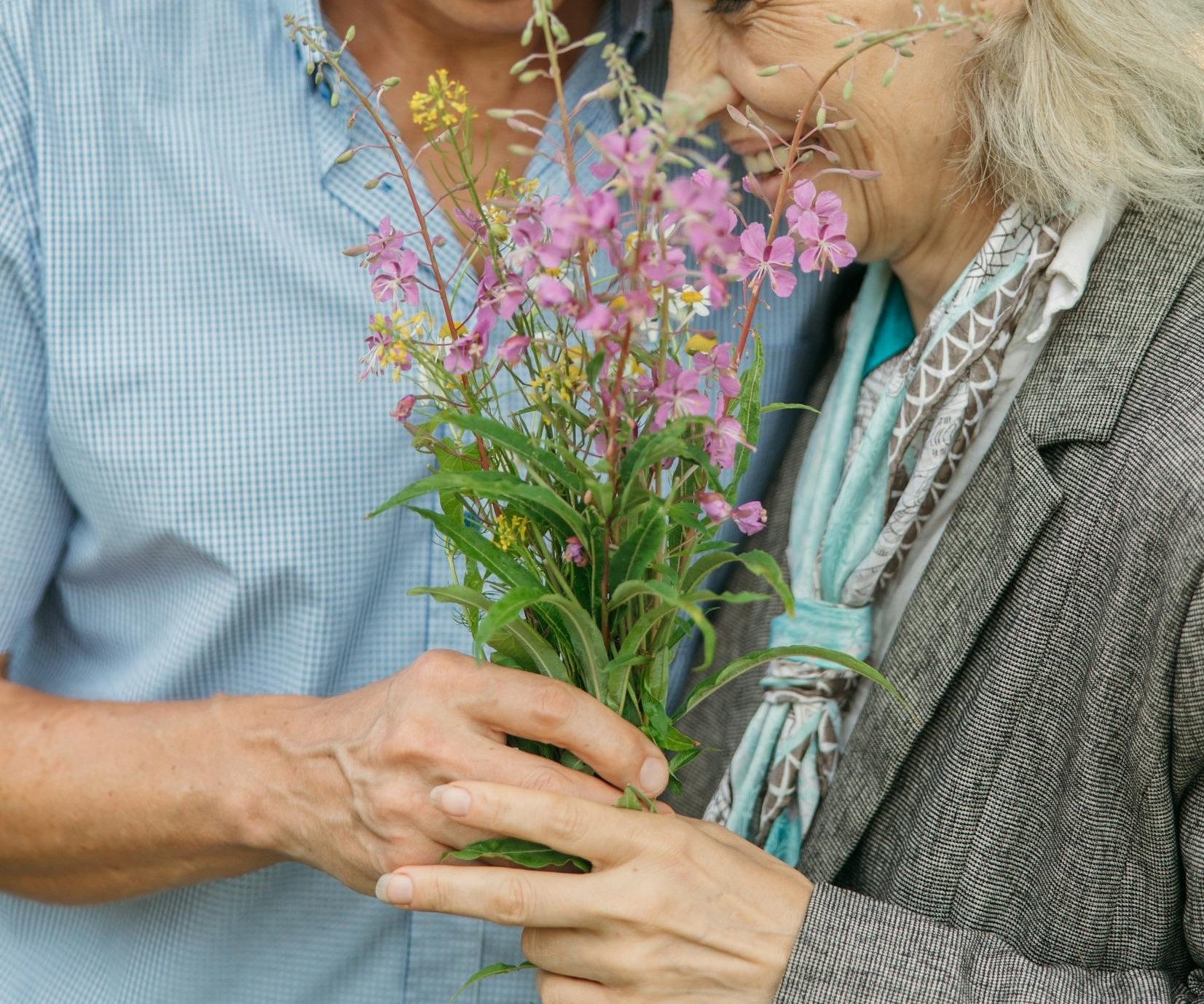 Primer plano de una feliz pareja de ancianos sosteniendo flores | Fuente: Pexels