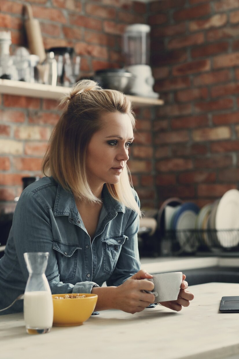 Una mujer reflexiva bebiendo café | Fuente: Freepik