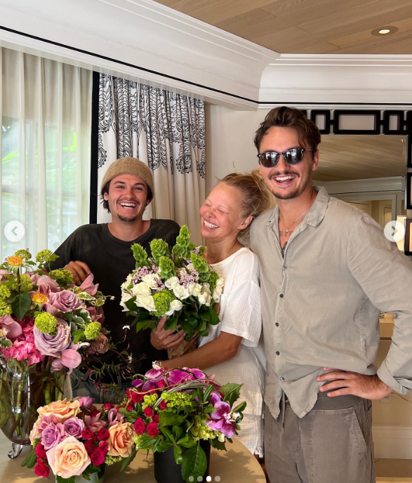 Pamela Anderson está radiante de alegría junto a sus hijos, Brandon Thomas Lee y Dylan Jagger Lee, rodeada por unos lujosos arreglos florales. Con un ramo de rosas blancas y hojas verdes en las manos, comparte una risa cariñosa con los chicos que la han ayudado a construir una vida tranquila y un jardín en la isla de Vancouver. Para celebrar el vínculo familiar por el que siempre ha luchado, acompañó la publicación del Día de la Madre con este mensaje: "Paz, amor, alegría… Bendiciones para todas las madres del mundo 🤍". | Fuente: Instagram/pamelaanderson
