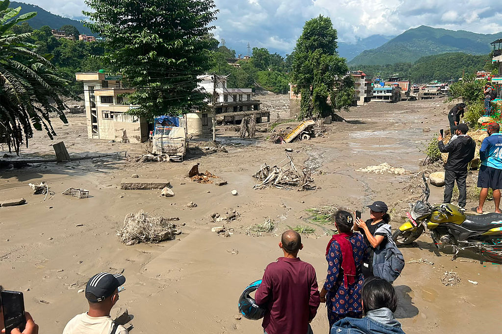 Residentes observan casas parcialmente sumergidas en agua lodosa tras inundaciones repentinas en Trishuli Bazar, distrito de Nuwakot, Nepal, el 26 de agosto de 2026. | Fuente: Getty Images