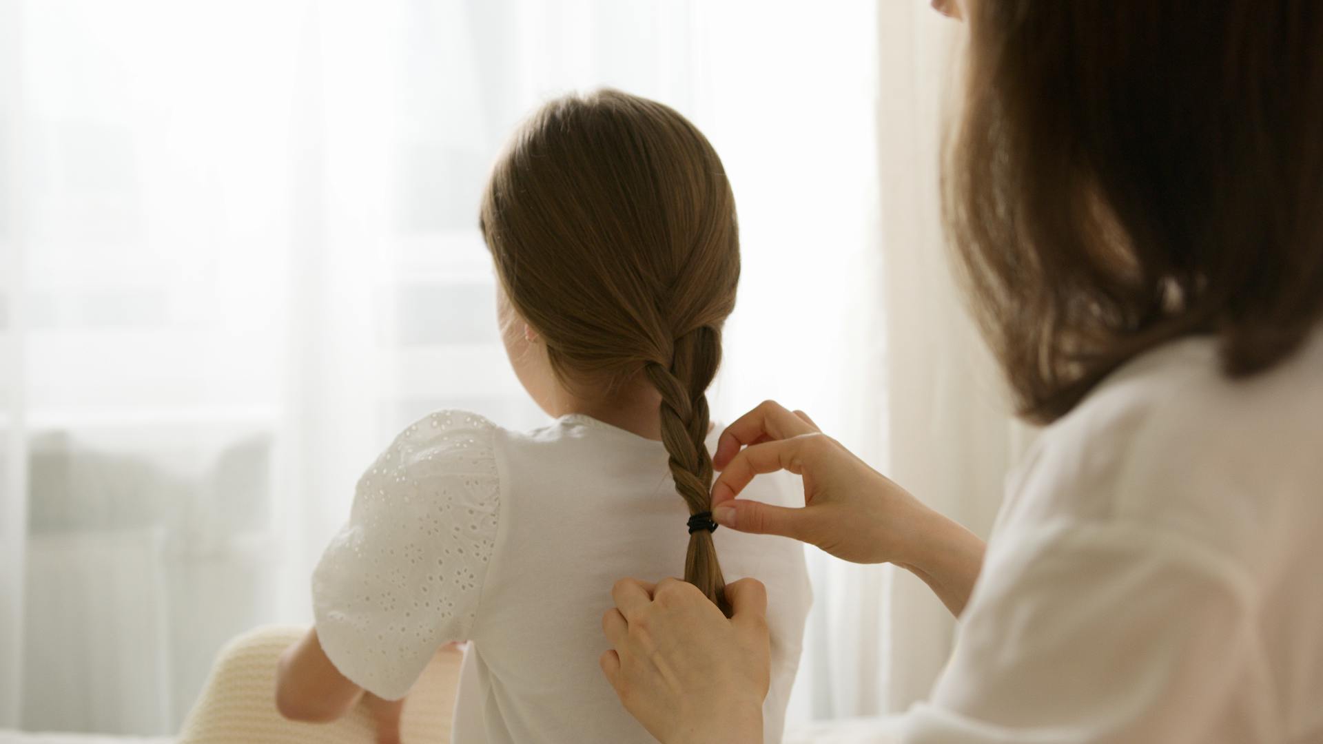 Una mujer trenzando el pelo de una niña | Fuente: Pexels