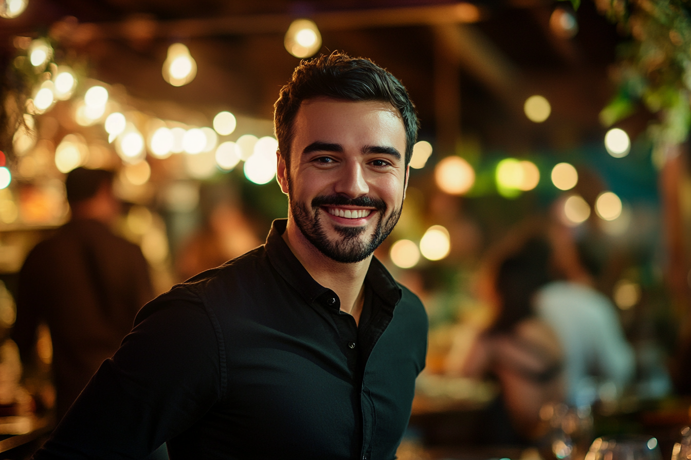 Un hombre sonriendo cálidamente, de pie en un bonito restaurante | Fuente: Midjourney