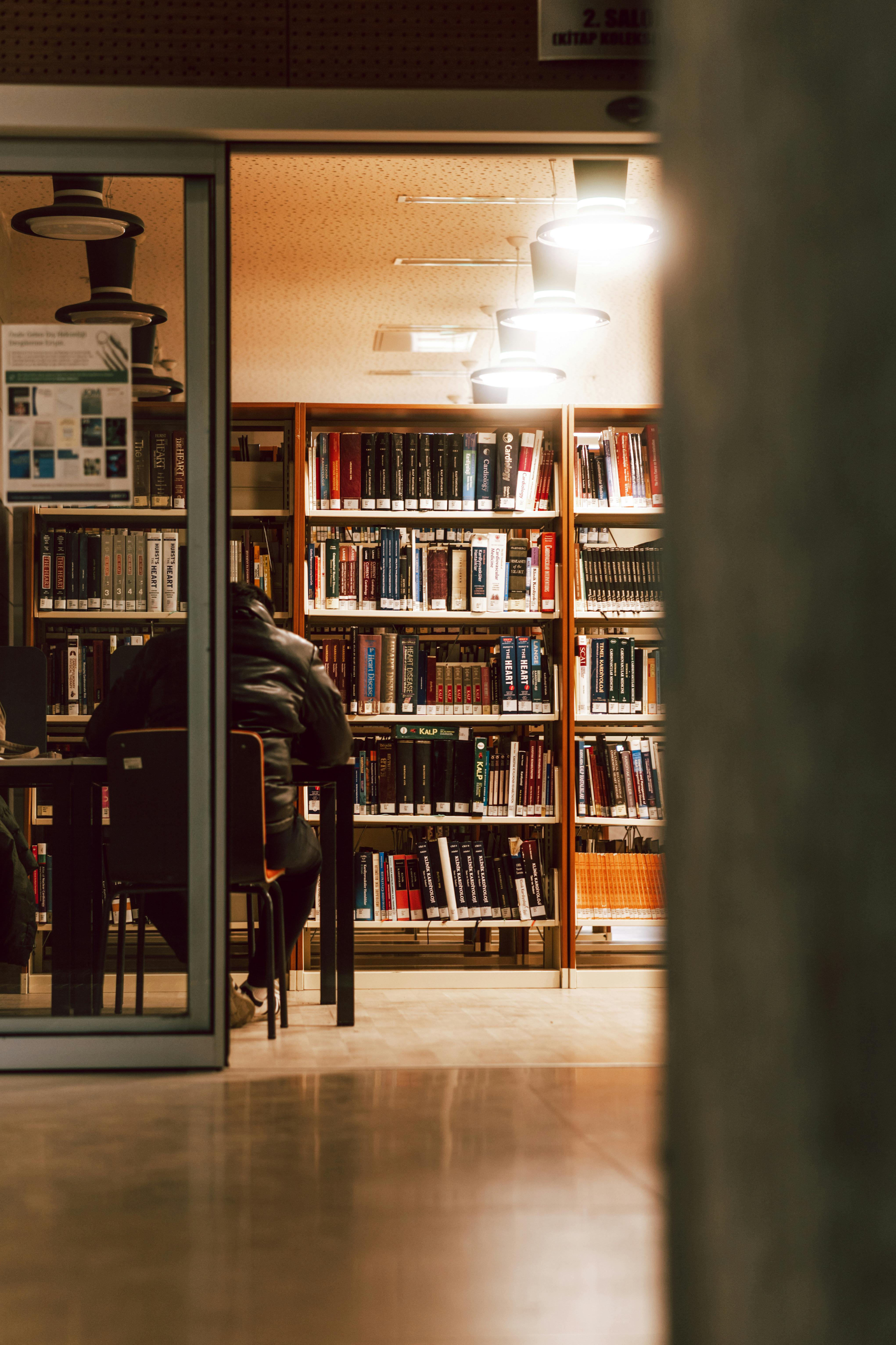Un hombre sentado en una librería | Fuente: Pexels