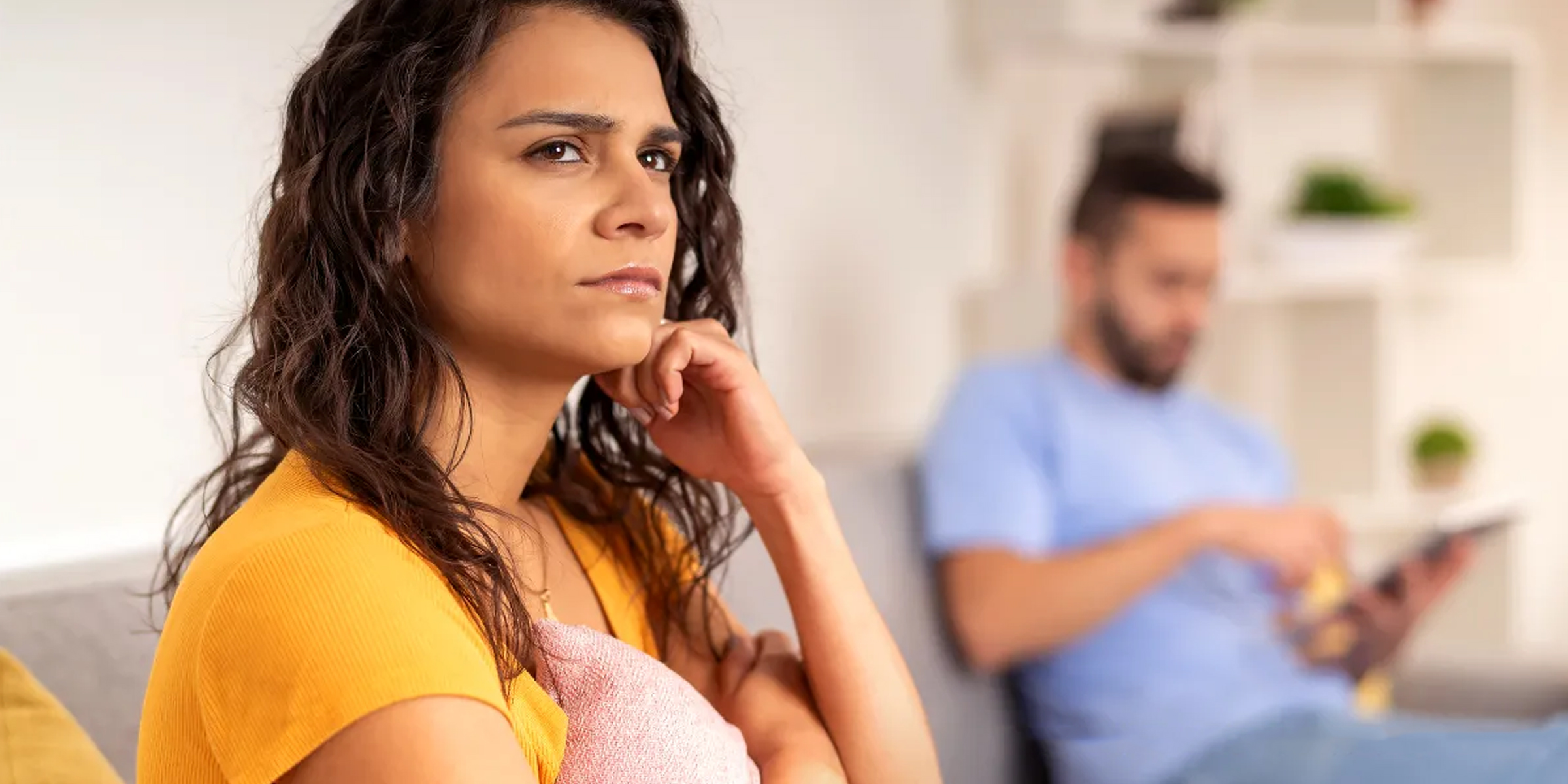 Una mujer seria perdida en sus pensamientos mientras está sentada junto a su pareja | Fuente: Shutterstock